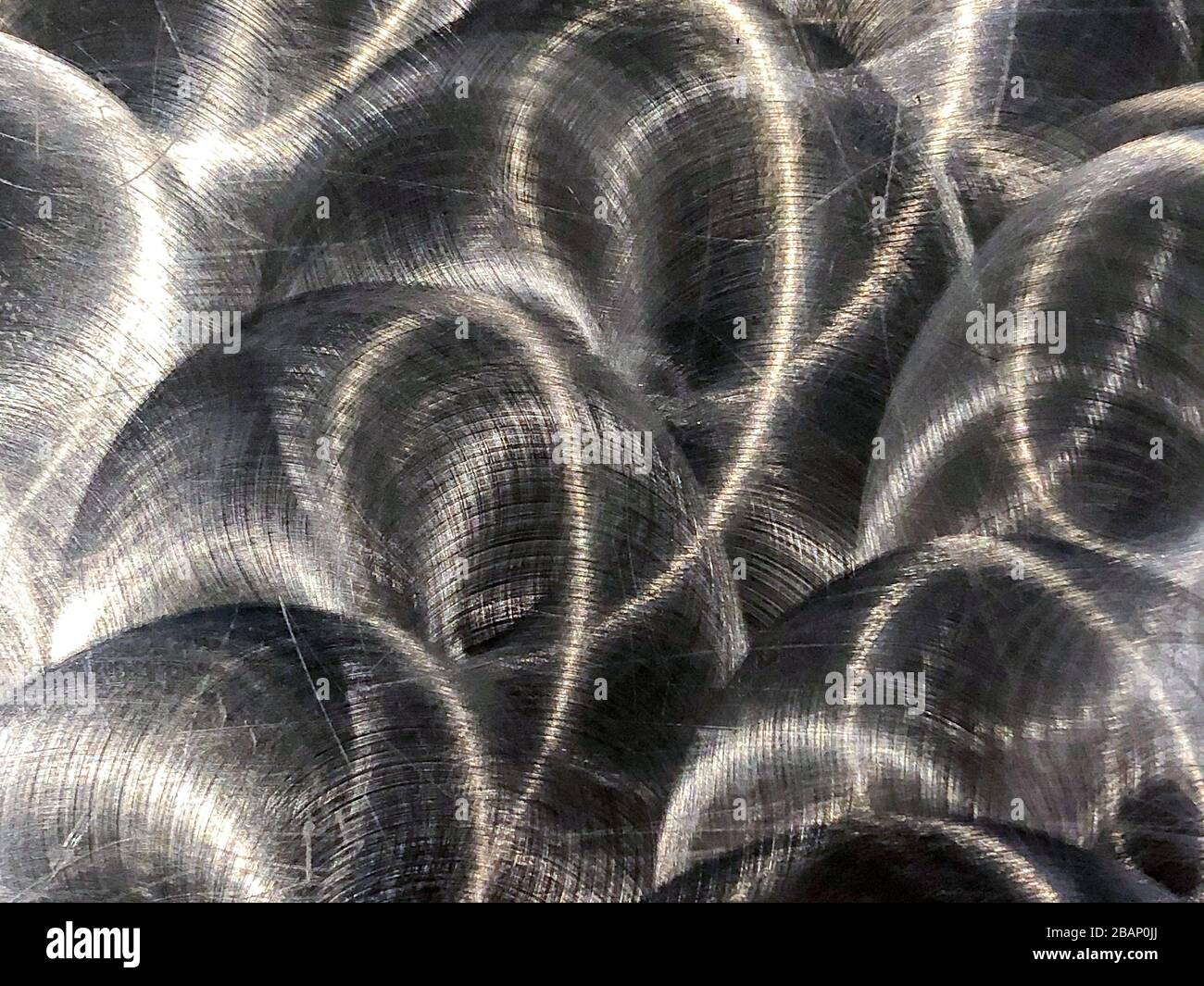 Nahaufnahme aus gebürstetem Metall, das kreisförmige, grunzende Muster hat Stockfoto