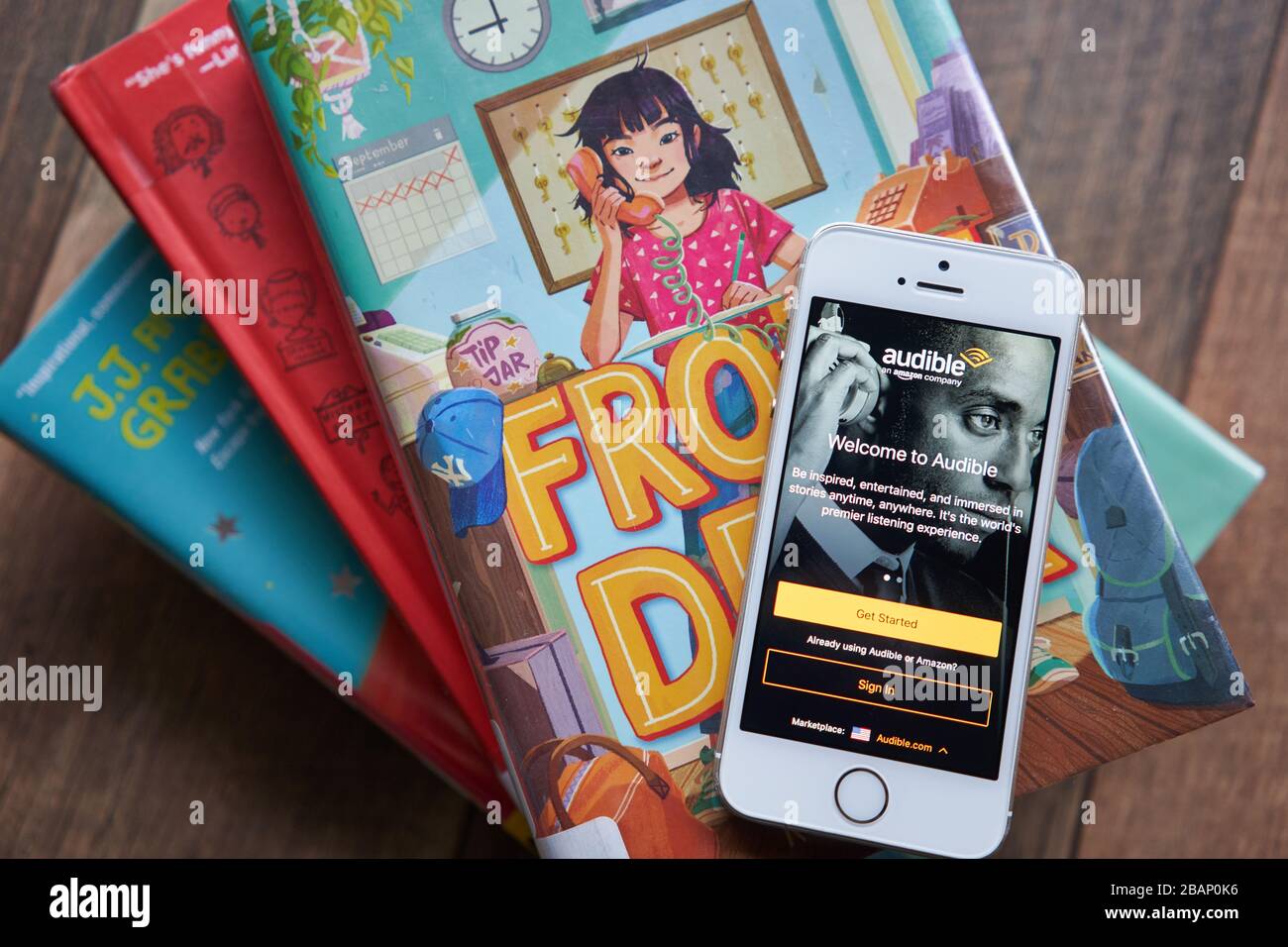Die Anmeldeseite für die Audible Mobile App wird auf einem Smartphone in den Büchern der Bibliothek angezeigt. Audible, das sich im Besitz von Amazon Inc. Befindet, hat den weltweit größten Katalog von Hörbüchern. Stockfoto