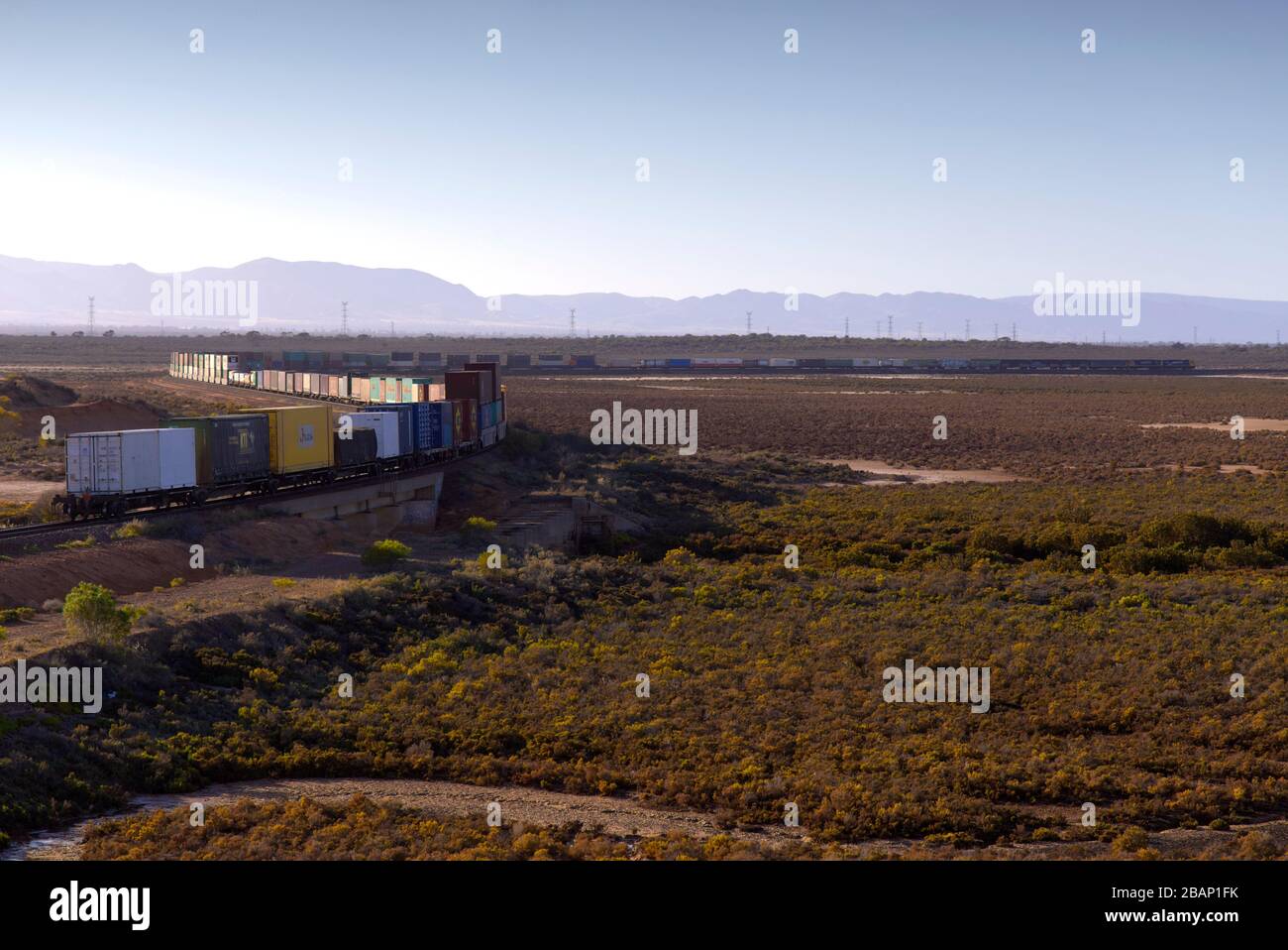 Güterzug transportiert doppelt gestapelte Module - Transportbehälter über die flache Landschaft in der Nähe von Port Auguata South Australia Stockfoto