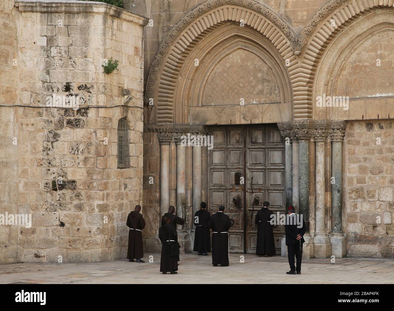 Peking, China. März 2020. Der katholische Klerus betet vor der verschlossenen Tür der Grabeskirche in der Altstadt von Jerusalem inmitten einer Coronavirus-Pandemie am 27. März 2020. Credit: Muammar Awad/Xinhua/Alamy Live News Stockfoto