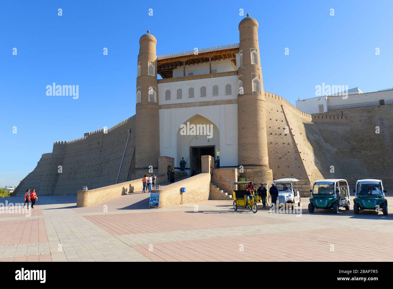 Mauer der Festung Buchara (Ark) mit Transportfahrzeugen wie Golfwagen für Touristen. Die massive Festung namens Arche von Buchara. Usbekistan. Stockfoto