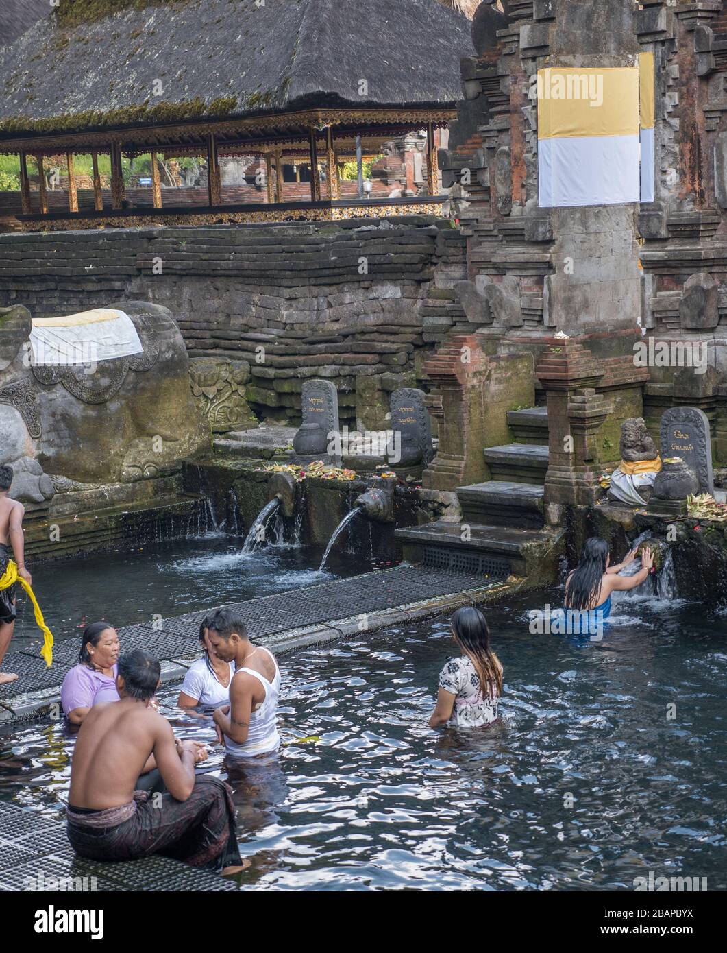 Lokale balinesische Anbeter baden am frühen Morgen im Pura Tirtha Empul (Weihwassertempel) mit nebeligem Sonnenlicht, das die Luft erfüllt. Stockfoto
