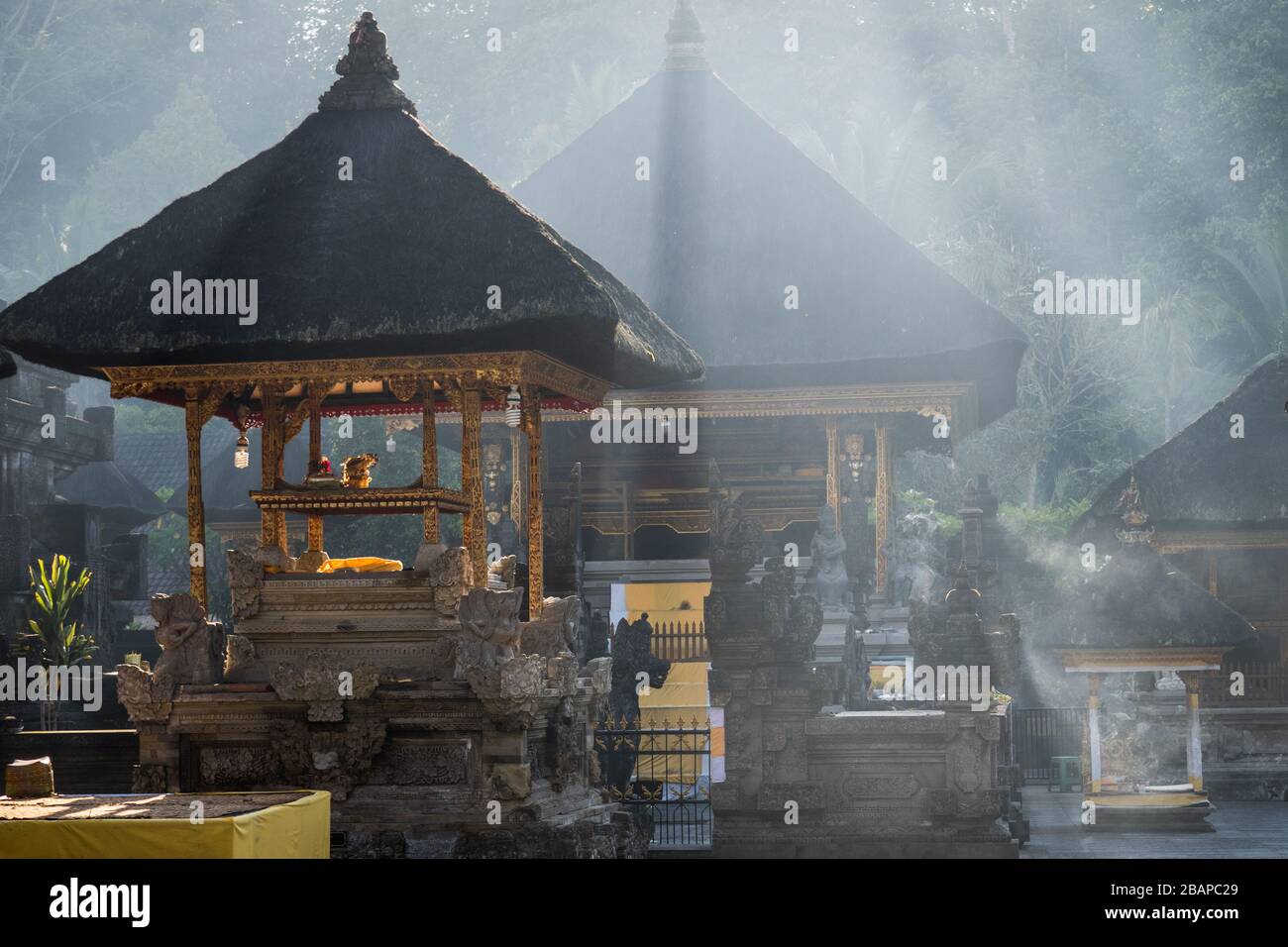 Die Sonne am frühen Morgen, die durch den Nebel strömt, der goldene Tempel in stimmungsvollem, schönem, trüben Licht im Pura Tirth Empul, balinesischem Wassertempel, einhüllt. Stockfoto