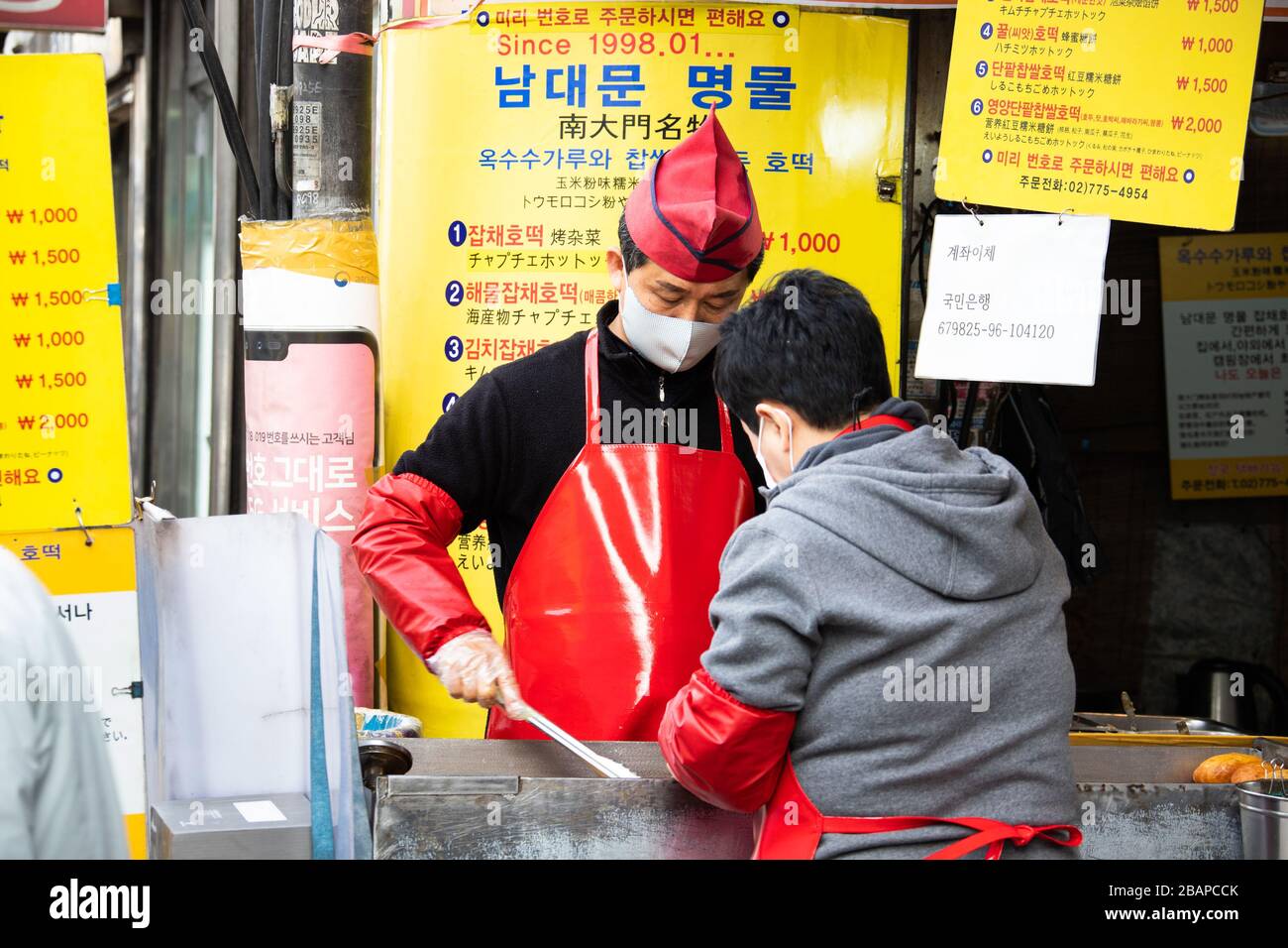 Anbieter von Straßennahrungsmitteln, der während der Coronavirus Pandemie, Seoul, Südkorea, eine Schutzmaske trägt Stockfoto