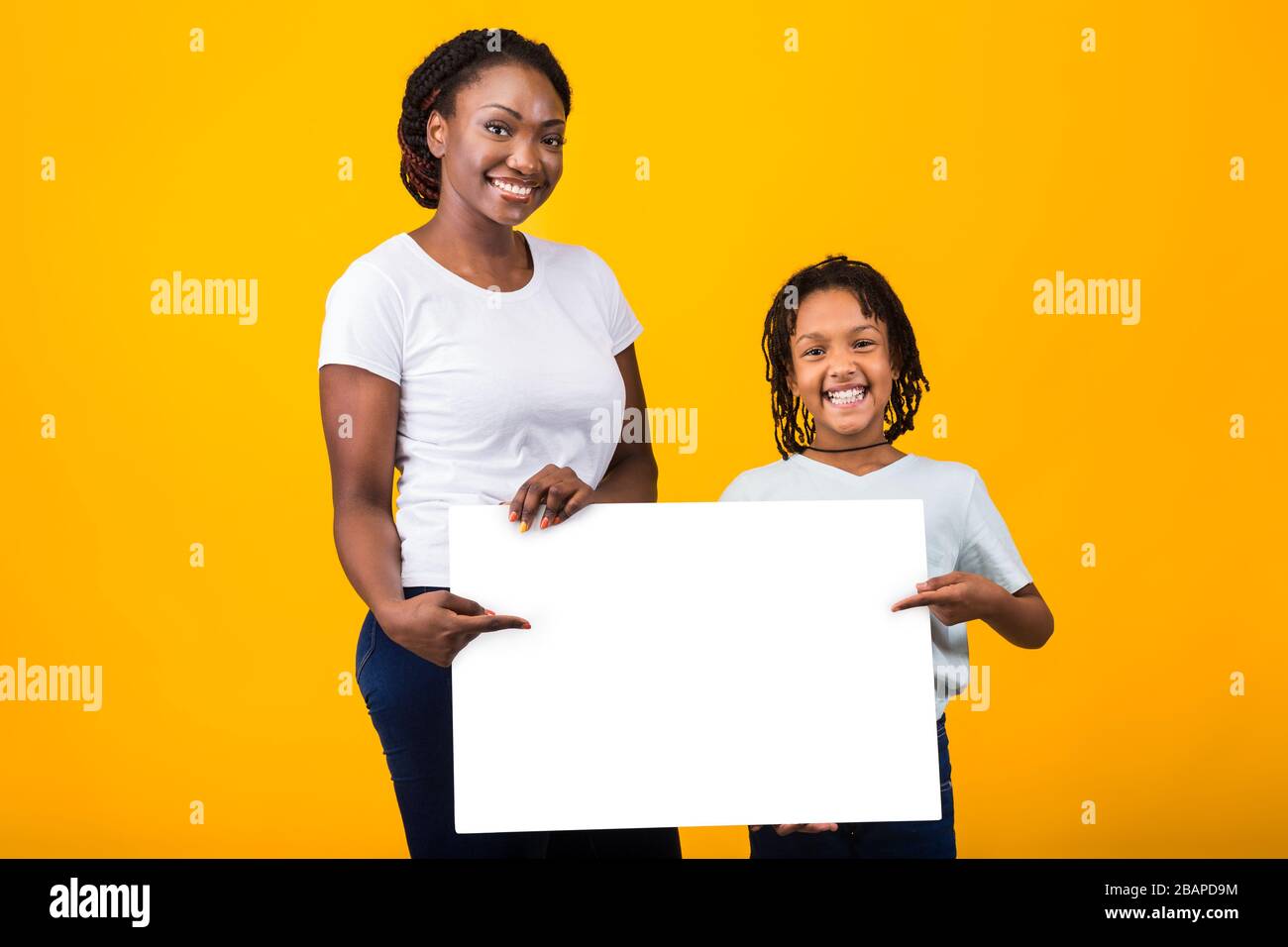 Fröhliche Familie mit weißem Schild im gelben Studio Stockfoto