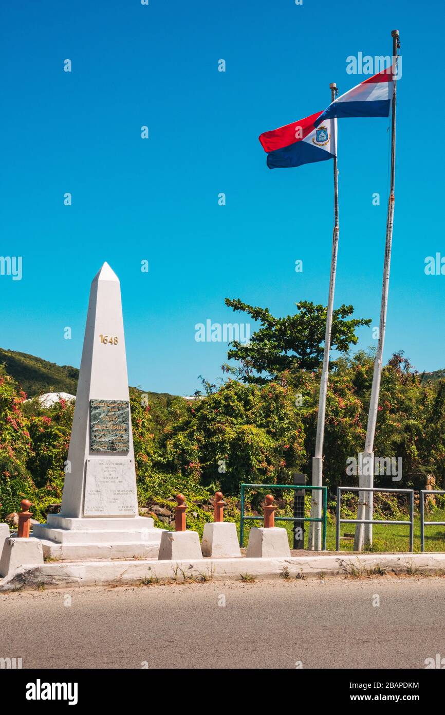Flaggen fliegen am Denkmal der Einheit und Freundschaft an der Grenze zwischen der französischen und niederländischen Seite der Karibikinsel St. Martin / St. Maarten Stockfoto