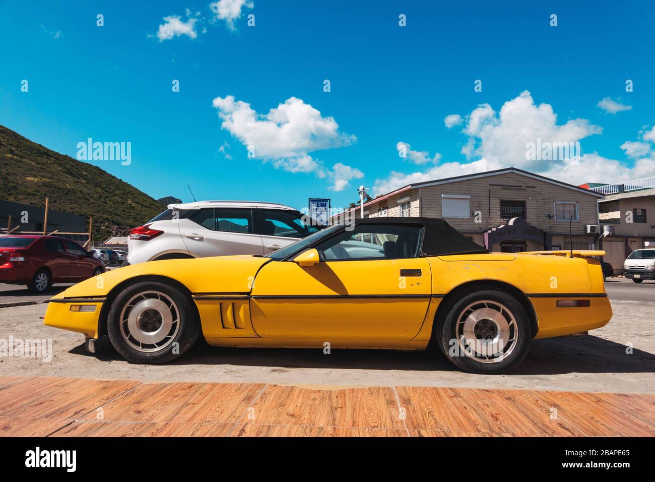 Ein altes gelbes 80er Jahre Chevrolet Corvette C4 Cabrio parkte in Philipsburg, St. Maarten Stockfoto