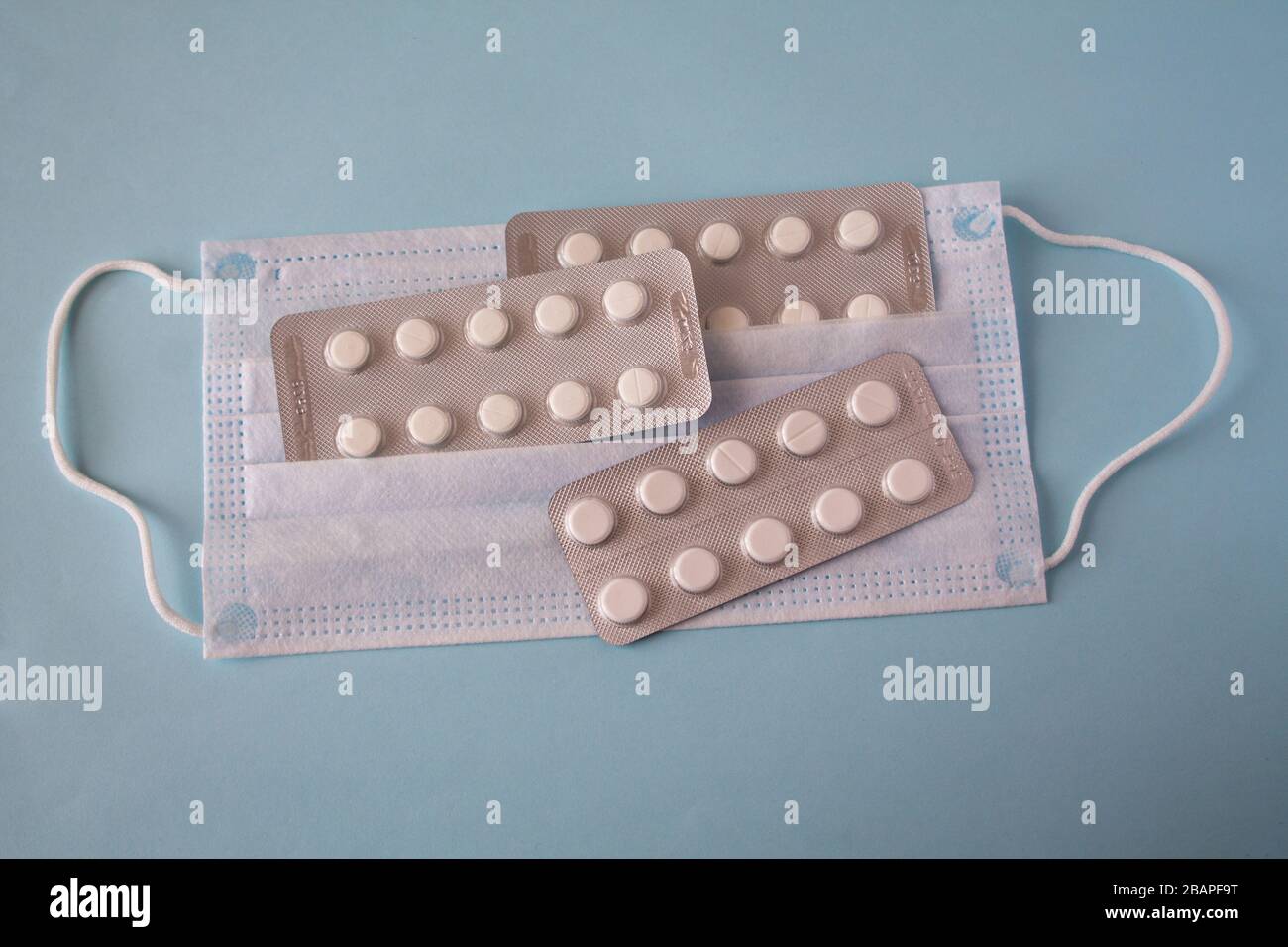 Medizinische Maske und weiße Tabletten. Pandemie verbreitet sich weltweit. Medizinische Behandlung der Infizierten. Gesundheitswesen Stockfoto
