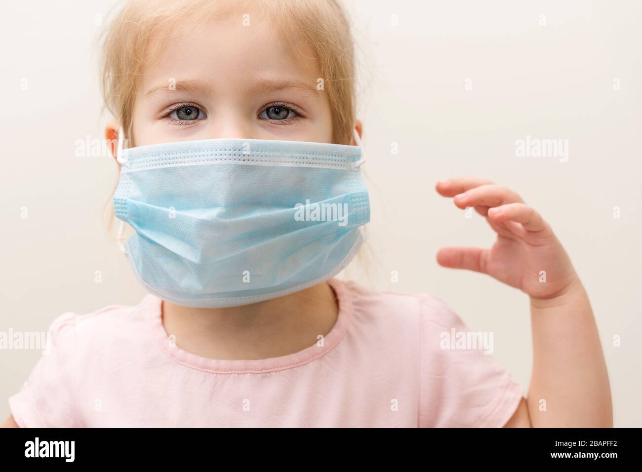 Kleines Mädchen in einer Einwegmaske auf hellem Hintergrund. Schutz vor chinesischer Virus-Epidemie Stockfoto