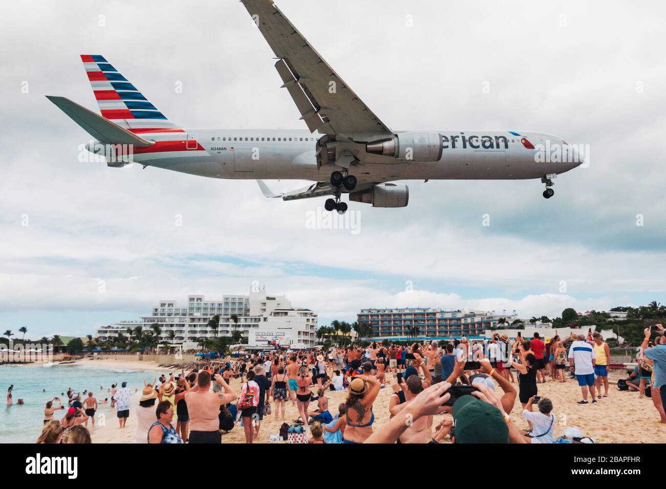 Eine Boeing 767-300er von American Airlines pfeift über einen Maho Beach, der mit Touristen von einem Kreuzfahrtschiff überfüllt ist, während sie bei Sint Maarten landet Stockfoto