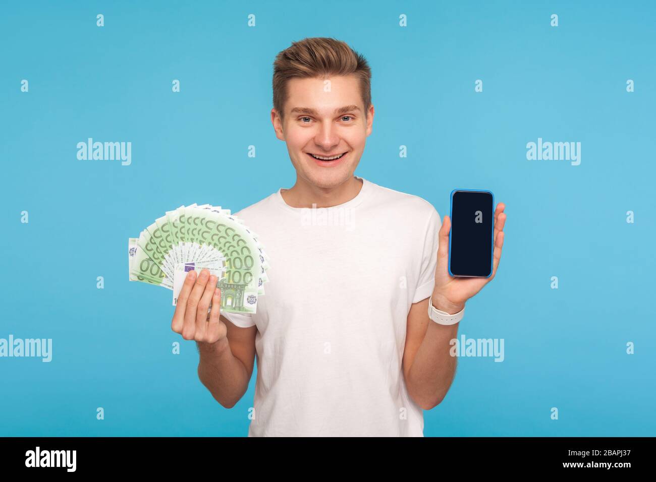 Zahlung und Überweisungen, Online-Banking. Fröhlicher lächelnder Mann im T-Shirt mit Euro-Banknoten und Smartphone, Werbung für Finanztransaktions-App. i Stockfoto