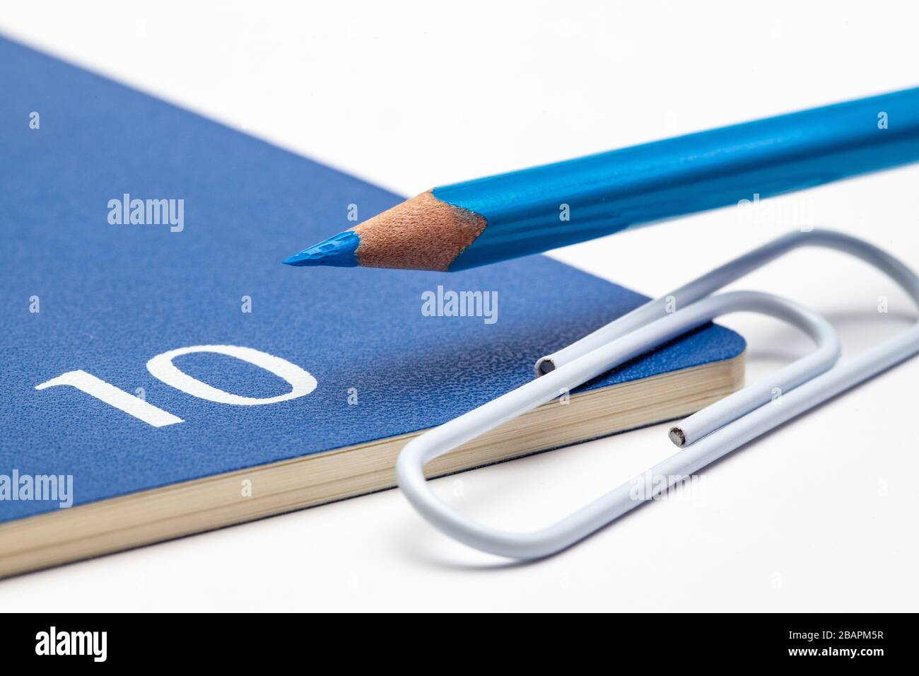 Veranstalter für den Monat Oktober, blauer Bleistift und weißer Büroklammer auf dem weißen Tisch. Stockfoto