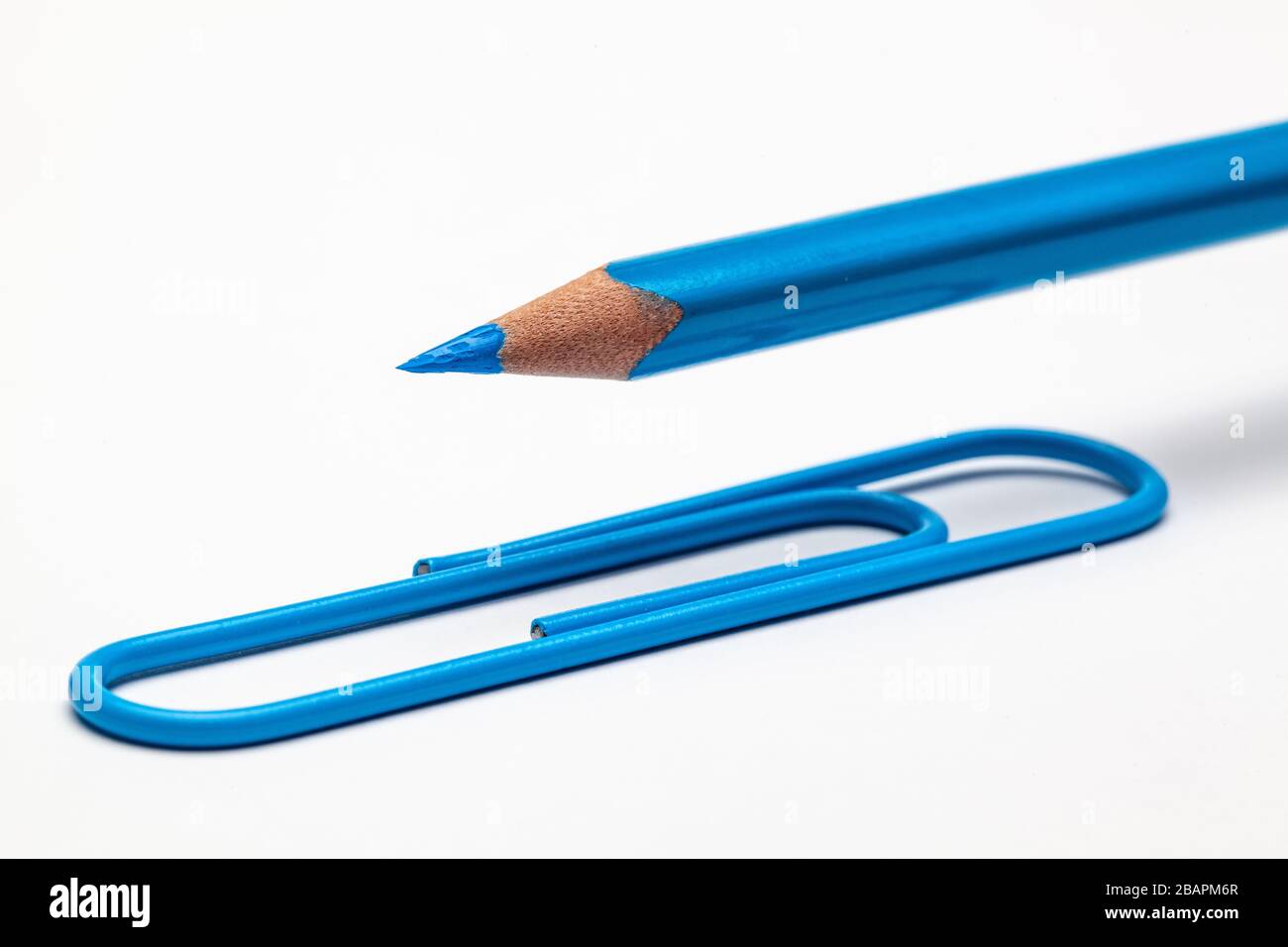 Blauer Bleistift und Büroklammer auf dem weißen Bürotisch. Stockfoto