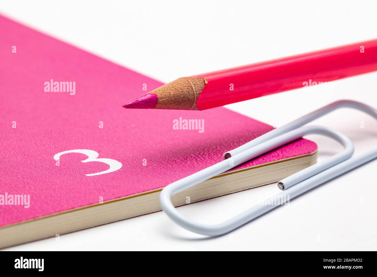 Veranstalter für den Monat März, pinkfarbener Bleistift und weiße Büroklammer auf dem weißen Tisch. Stockfoto