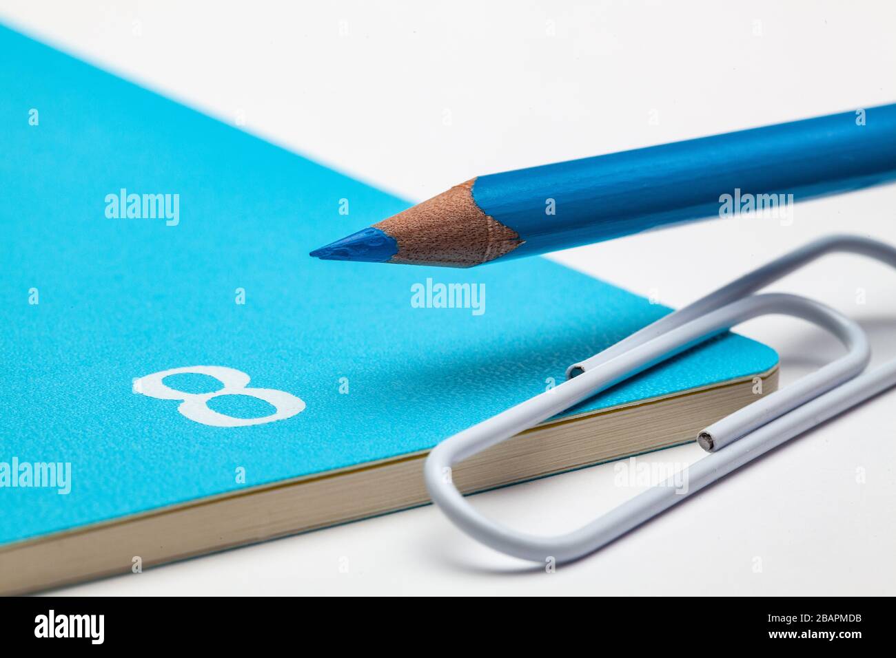 Veranstalter für den Monat August, blauer Bleistift und weiße Büroklammer auf dem weißen Tisch. Stockfoto
