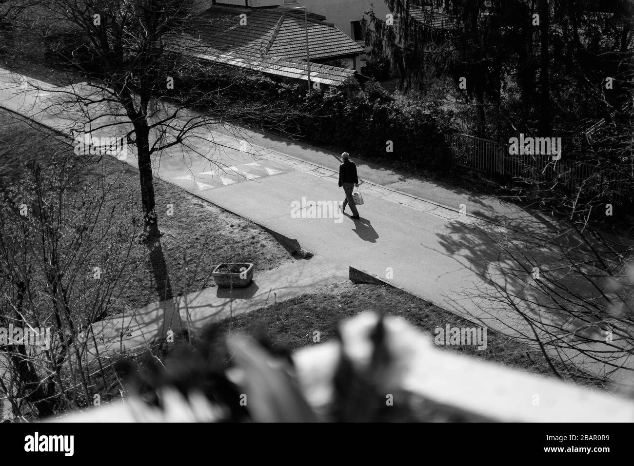 Kranj, Slowenien, 21. März 2020: Ein Mann, der vom Lebensmittelgeschäft zurückkehrt, läuft während des Coronavirus-Ausbruchs landesweit eine leere Straße hinunter. Stockfoto