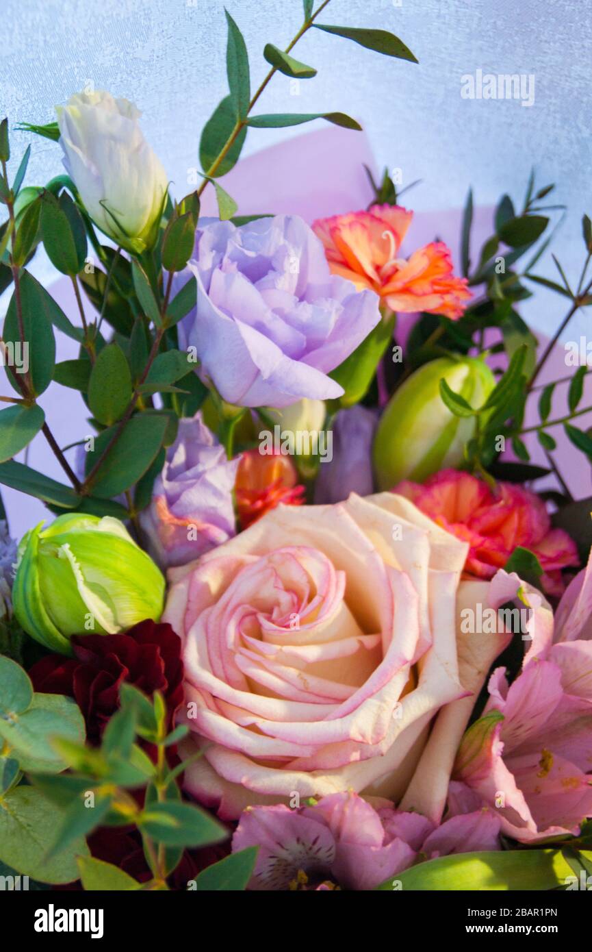 Feiner Blumenstrauß aus verschiedenen Blumen in rosafarbener Verpackung. Nahaufnahme des vertikalen Fotos. Stockfoto