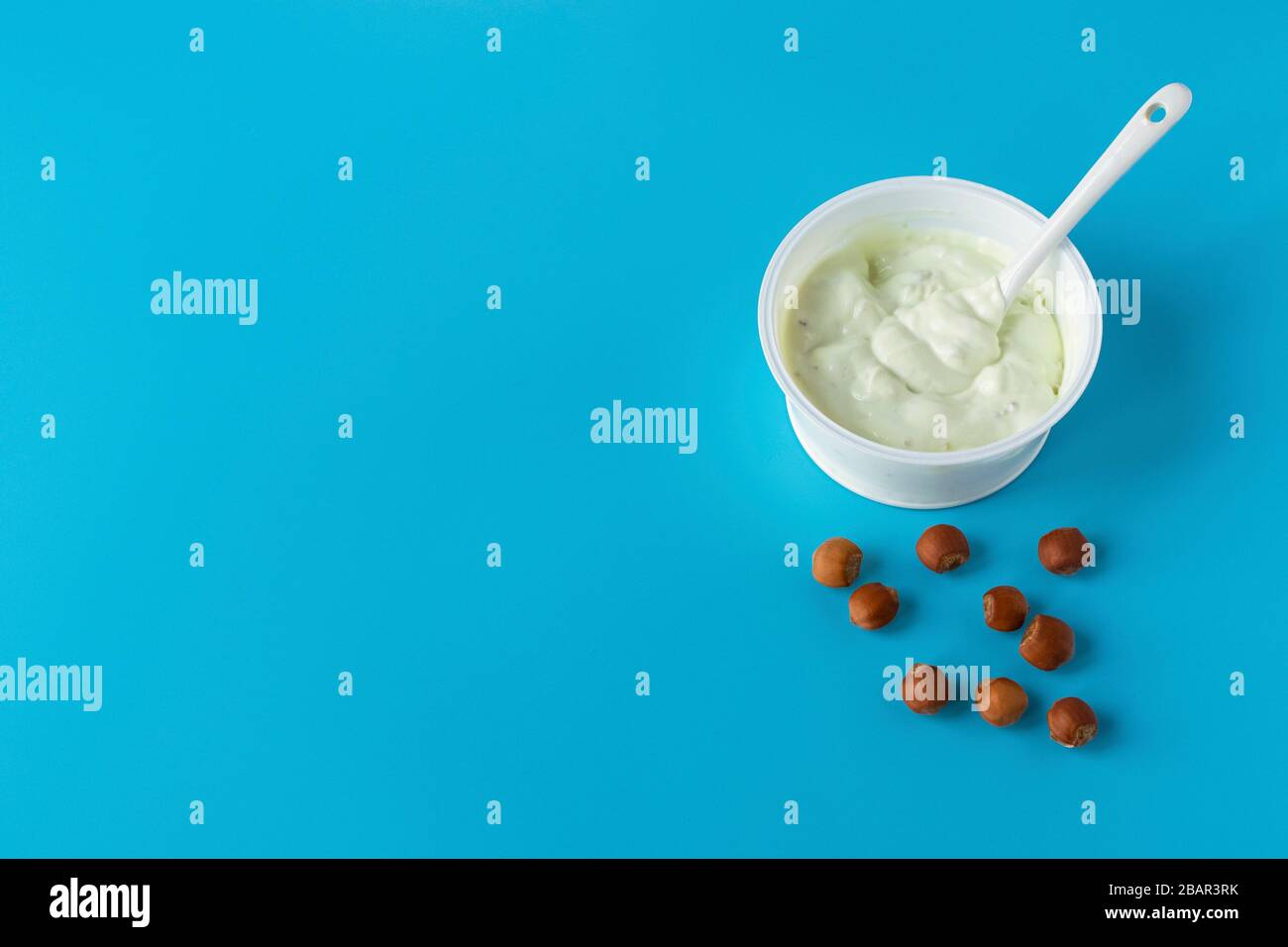 Joghurt in einem Glas auf blauem Grund mit Nüssen. Ein gesundes leichtes Diät-Frühstück. Milchprodukte. Stockfoto