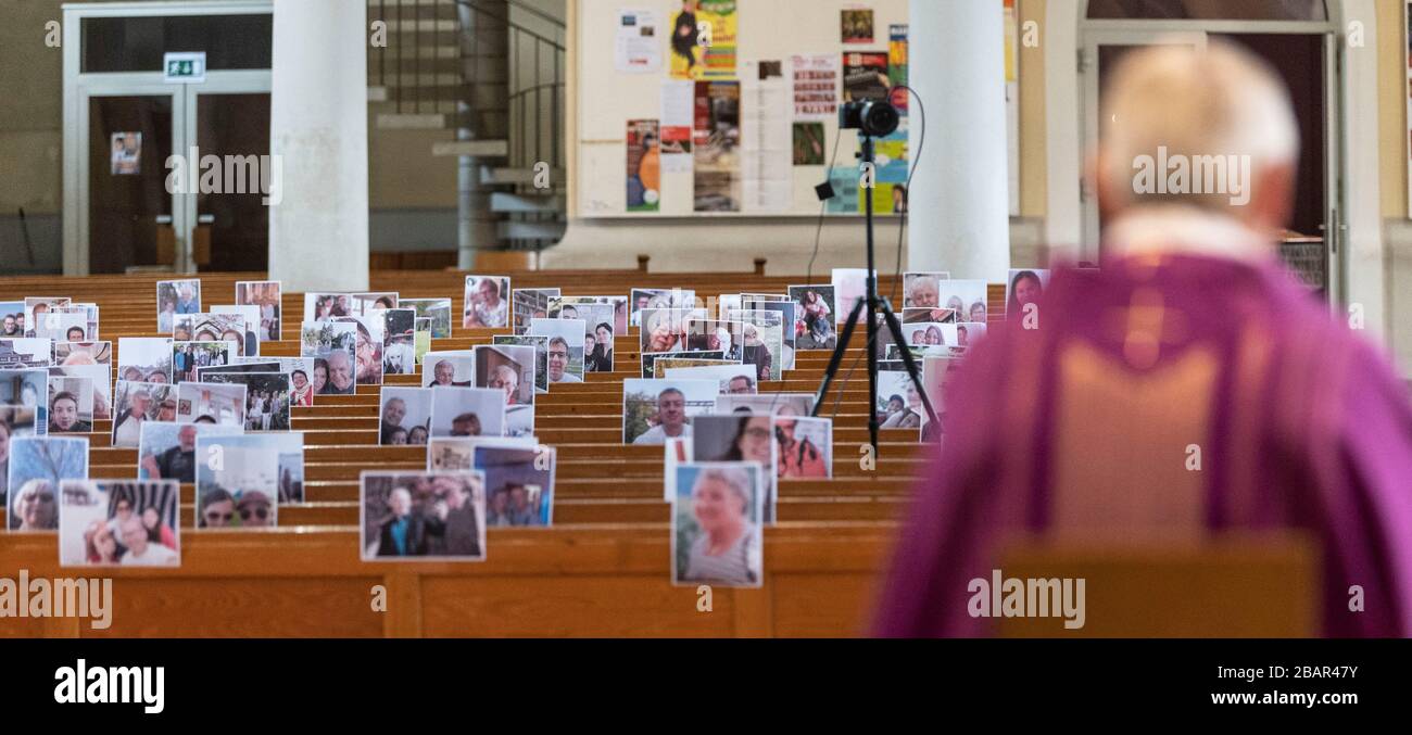 Achern, Deutschland. März 2020. Pfarrer Joachim Giesler sitzt in der Pfarrkirche vor Fotos mit Gemeindemitgliedern. Gottesdienste finden wegen des Coronavirus vor leeren Kirchen statt. Die Pfarrei hatte ihre Gemeindemitglieder gebeten, Bilder zu senden. Mehr als 300 Bilder wurden ausgedruckt und an den Kirchenbänken aufgehängt. Credit: Patrick Seeger / dpa / Alamy Live News Stockfoto