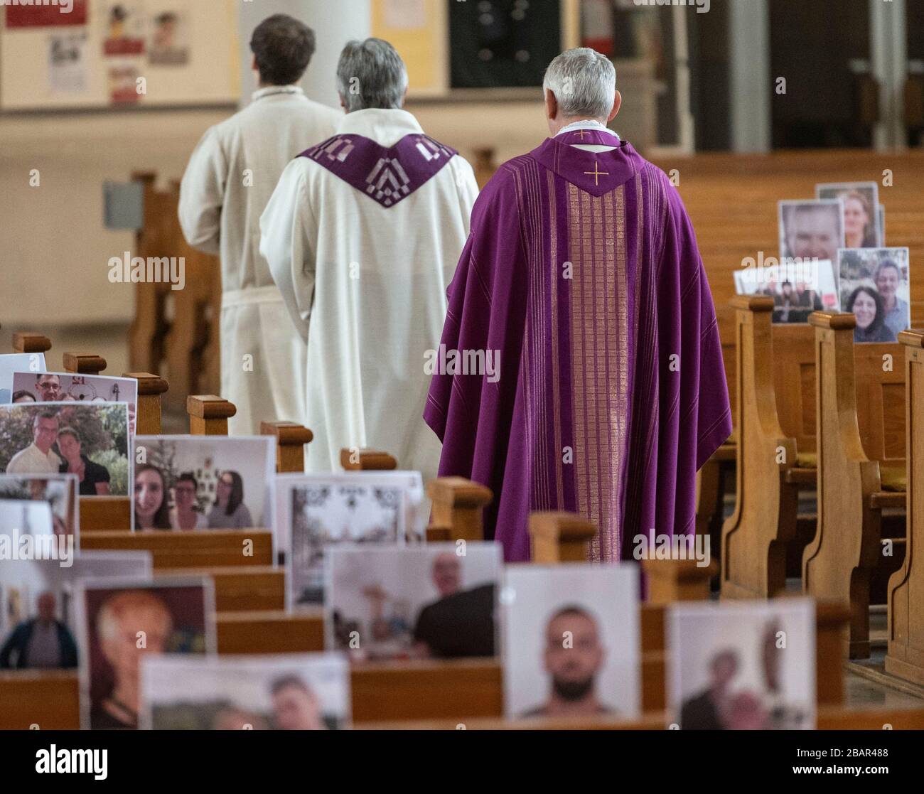 Achern, Deutschland. März 2020. Pfarrer Joachim Giesler (h) geht mit Gemeindemitgliedern in der Pfarrkirche an Fotos vorbei. Gottesdienste finden wegen des Coronavirus vor leeren Kirchen statt. Die Pfarrei hatte ihre Gemeindemitglieder gebeten, Bilder zu senden. Mehr als 300 Bilder wurden ausgedruckt und an den Kirchenbänken aufgehängt. Credit: Patrick Seeger / dpa / Alamy Live News Stockfoto