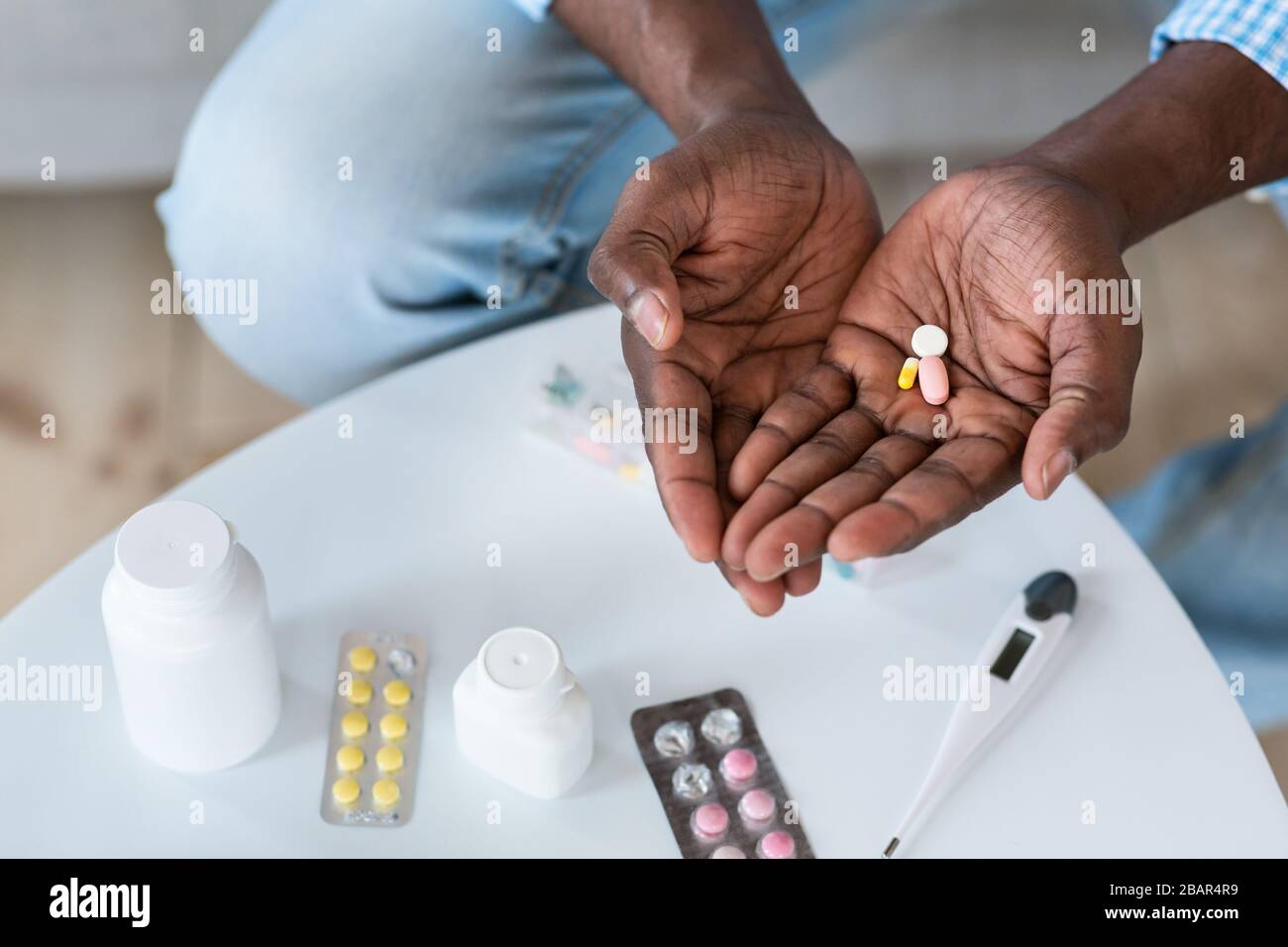 Coronavirus-Therapie. Nahaufnahme des afroamerikanischen Mannes, der Drogen im Haus hält, Draufsicht. Leerer Speicherplatz Stockfoto