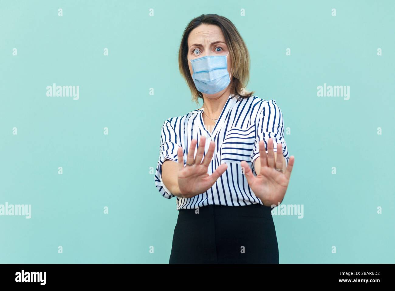 Halt, kommen Sie sich nicht näher. Porträt der schockierten Frau mit operativer medizinischer Maske stehen und zeigen Anschlag mit Handbangen. Medizin und Gesundheit Stockfoto