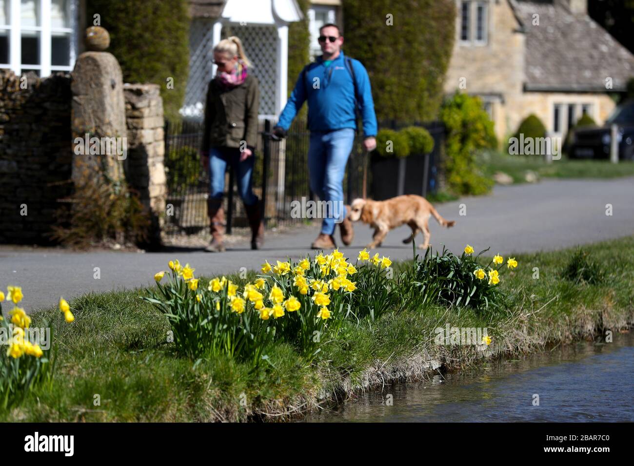 Hundegänger im Dorf Lower Slaughter in den Cotswolds, Gloucestershire, während die Uhren eine Stunde nach British Summer Time (BST) vorrücken. Stockfoto