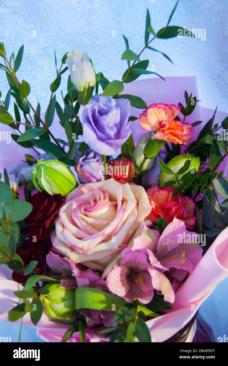 Feiner Blumenstrauß aus verschiedenen Blumen in rosafarbener Verpackung. Nahaufnahme des vertikalen Fotos. Stockfoto