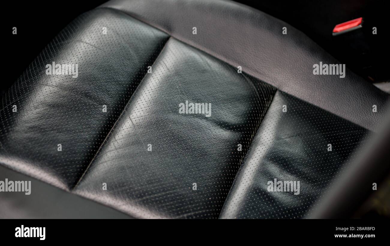 Schwarz perforierter Autositz aus Leder mit makro-nahen, isolierten Details. Weiße Lederkontur, schöner Stich, belüftete Sitze, geringe Laufleistung. Stockfoto