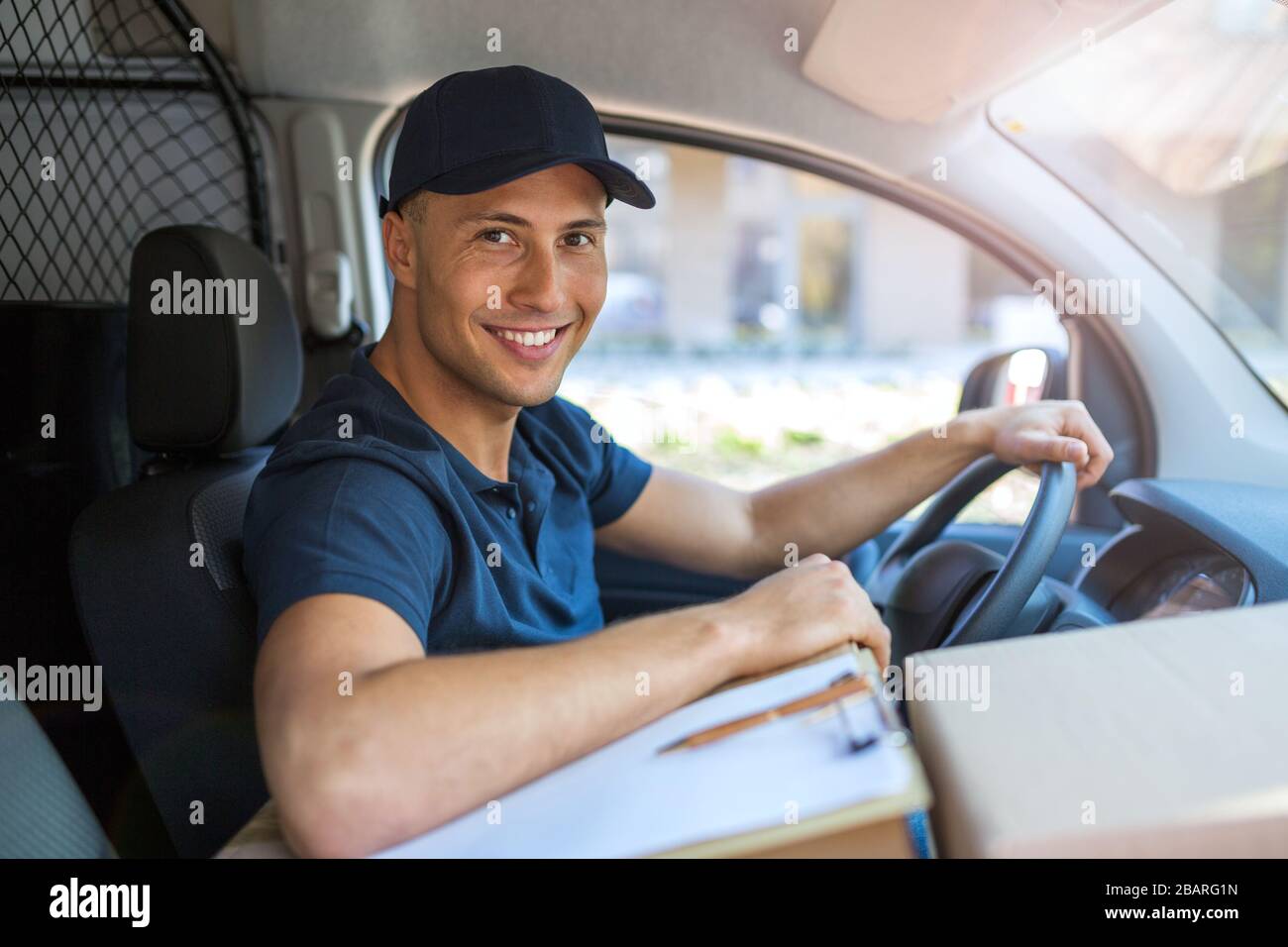 Lächelnder Liefermann mit seinem Lieferwagen Stockfoto
