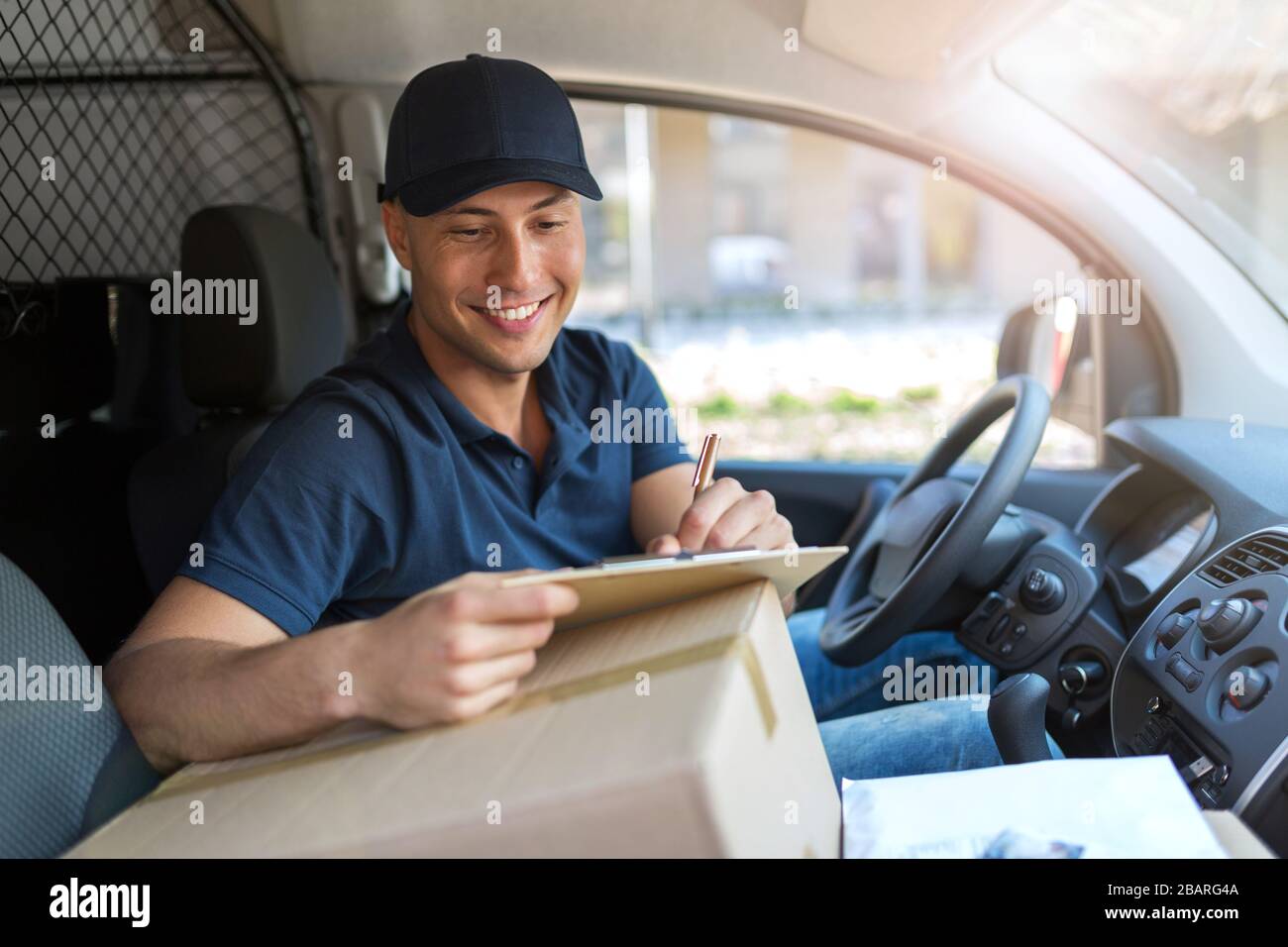 Lächelnder Liefermann mit seinem Lieferwagen Stockfoto