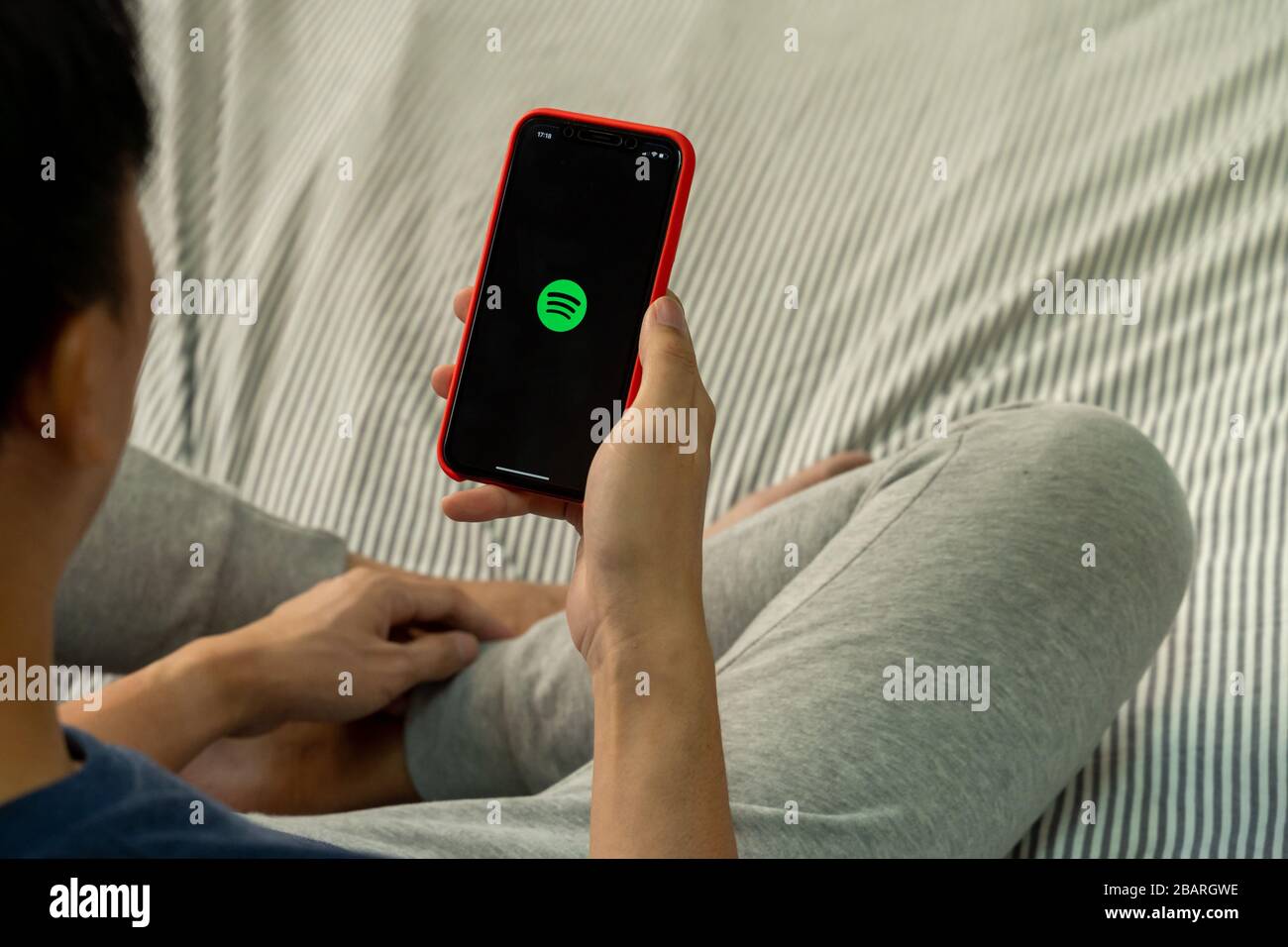 BANGKOK, THAILAND - 27. MÄRZ 2020: Ein Mann, der ein Telefon mit Screenshot von Spotify auf dem iPhone hält. Spotify ist ein internationaler Mediendienstleister Stockfoto
