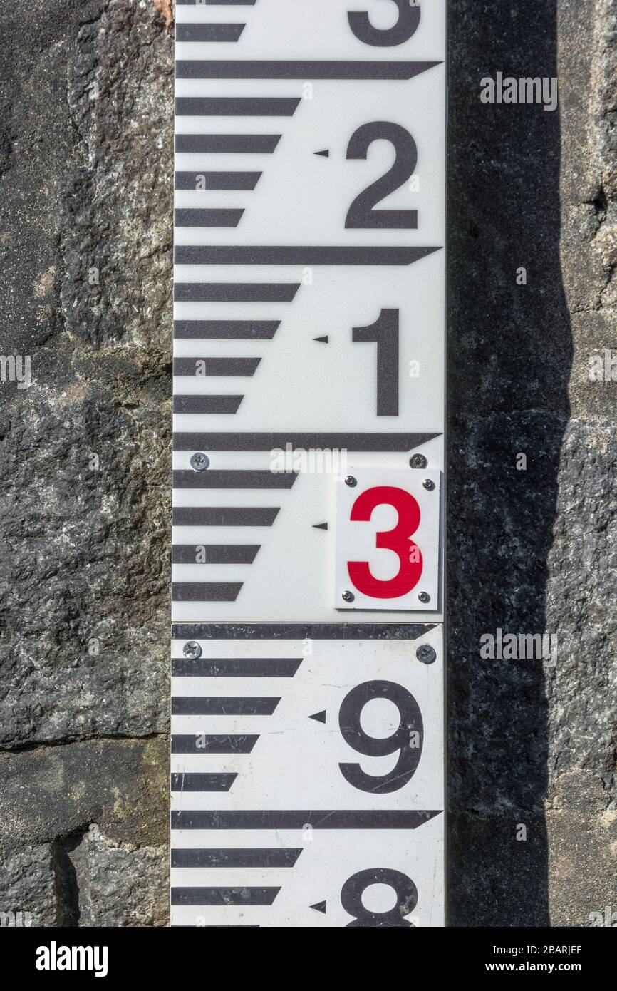 Flusswasserspiegel Messlehre an der abschüssigen Sperrmauer am River Fowey bei Lostwithiel. Metapher: Steigender Wasserstand, Hochwasserschutz. Stockfoto