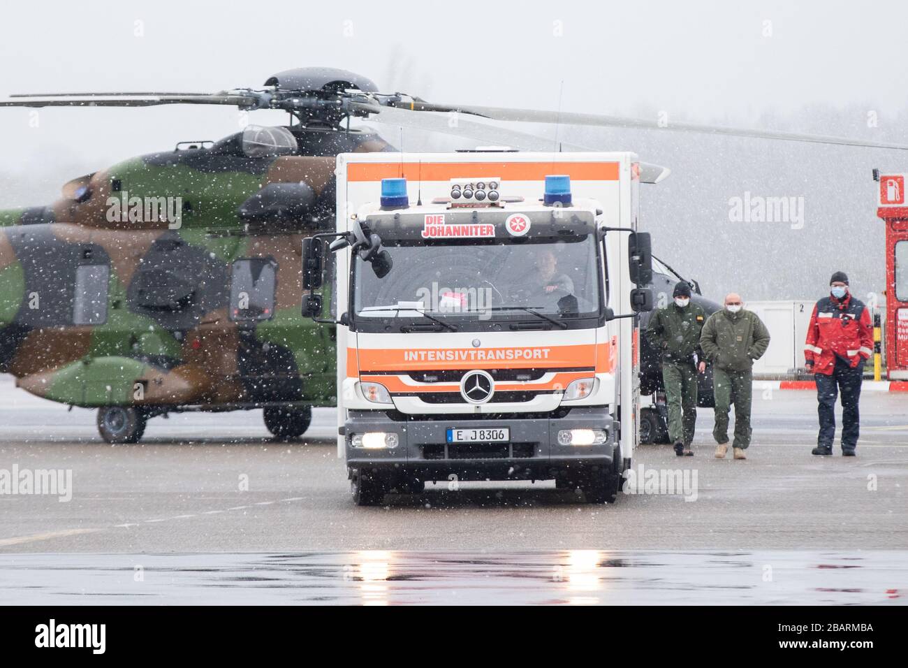 29. März 2020, Nordrhein-Westfalen, Mülheim an der Ruhrgebiet: Ein Intensivtransport der Johanniter fährt vor einem Militärhubschrauber über das Vorfeld des Flughafens. Der Hubschrauber wurde zum Transport von zwei Patienten aus dem französischen Metzer nach Mühlheim zur Behandlung am Universitätsklinikum Essen eingesetzt. Foto: Marcel Kusch / dpa Stockfoto