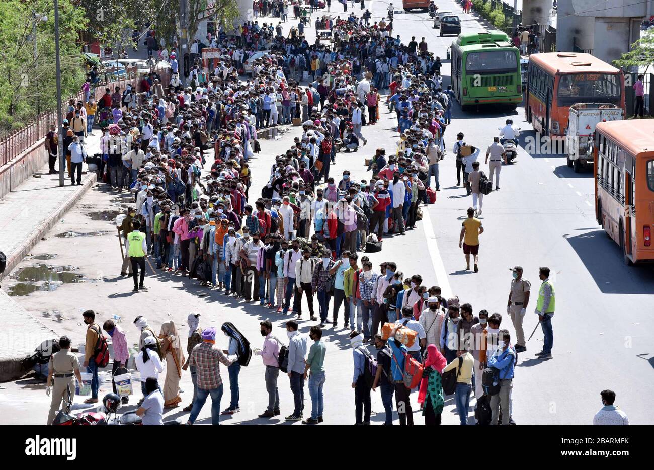 Wanderarbeiter, die in Schlangen warten, bevor sie am vierten Tag der landesweiten Sperrung in Uttar Pradesh (OBEN) einen provisorischen Busstand in Neu-Delhi betreten, um die Ausbreitung von Coronavirus zu verhindern (Foto von Sondeep Shankar/Pacific Press) Stockfoto