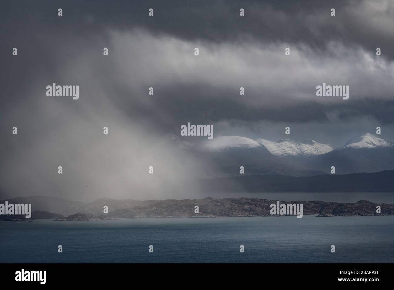 Bedrohliches Wetter auf der Insel Skye in Schottland mit Rassay in der Ferne, während sich Sturmwolken mit Regenbögen am Horizont bilden Stockfoto