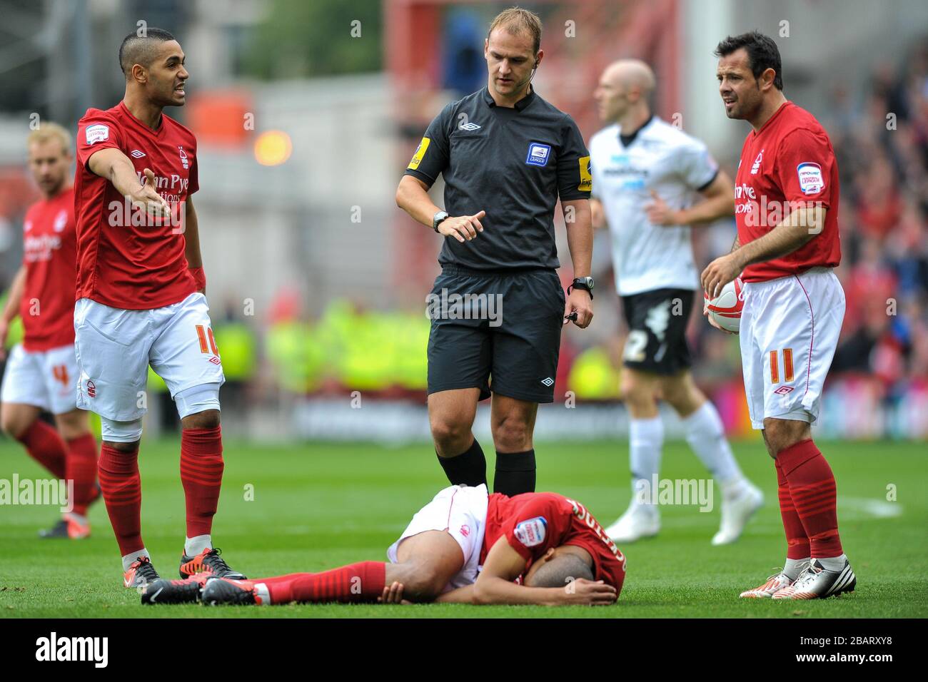 Der Dexter Blackstock von Nottingham Forest liegt verletzt, da Lewis McGugan (links) Schiedsrichter Robert Madley anspricht Stockfoto