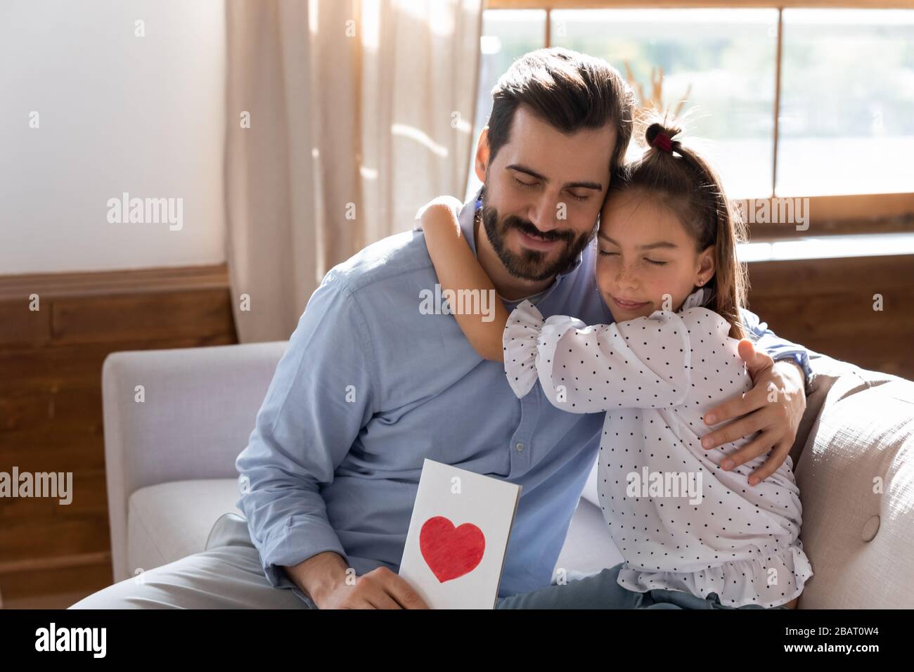 Der junge Vater umarmt die kleine Tochter und fühlt sich dankbar für die Glückwünsche zum Geburtstag. Stockfoto