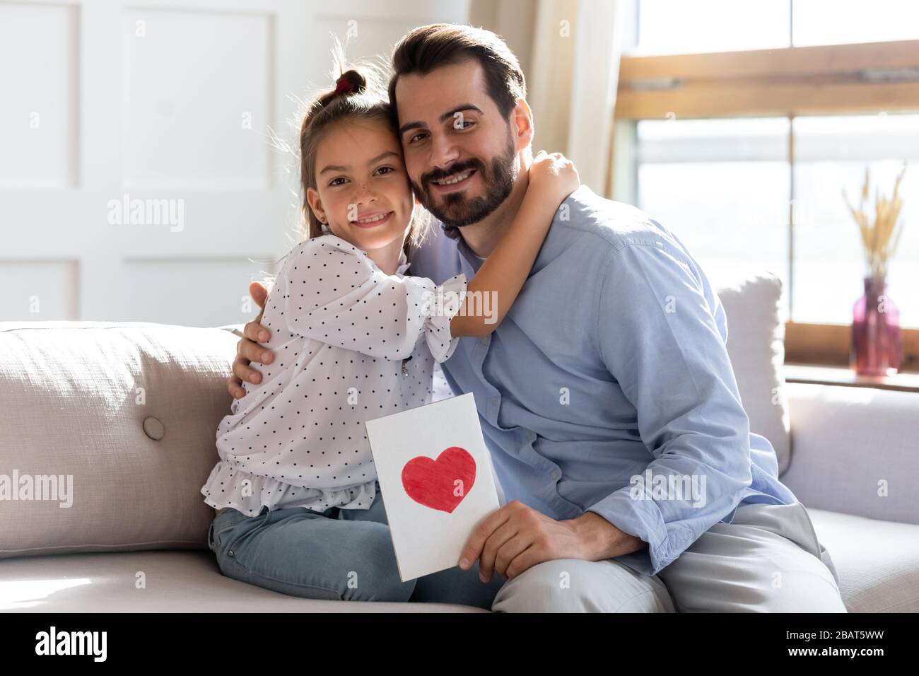 Portrait des süßen kleinen Mädchens, das lächelnden Vater umarmte, Glückwunsch zum Geburtstag. Stockfoto