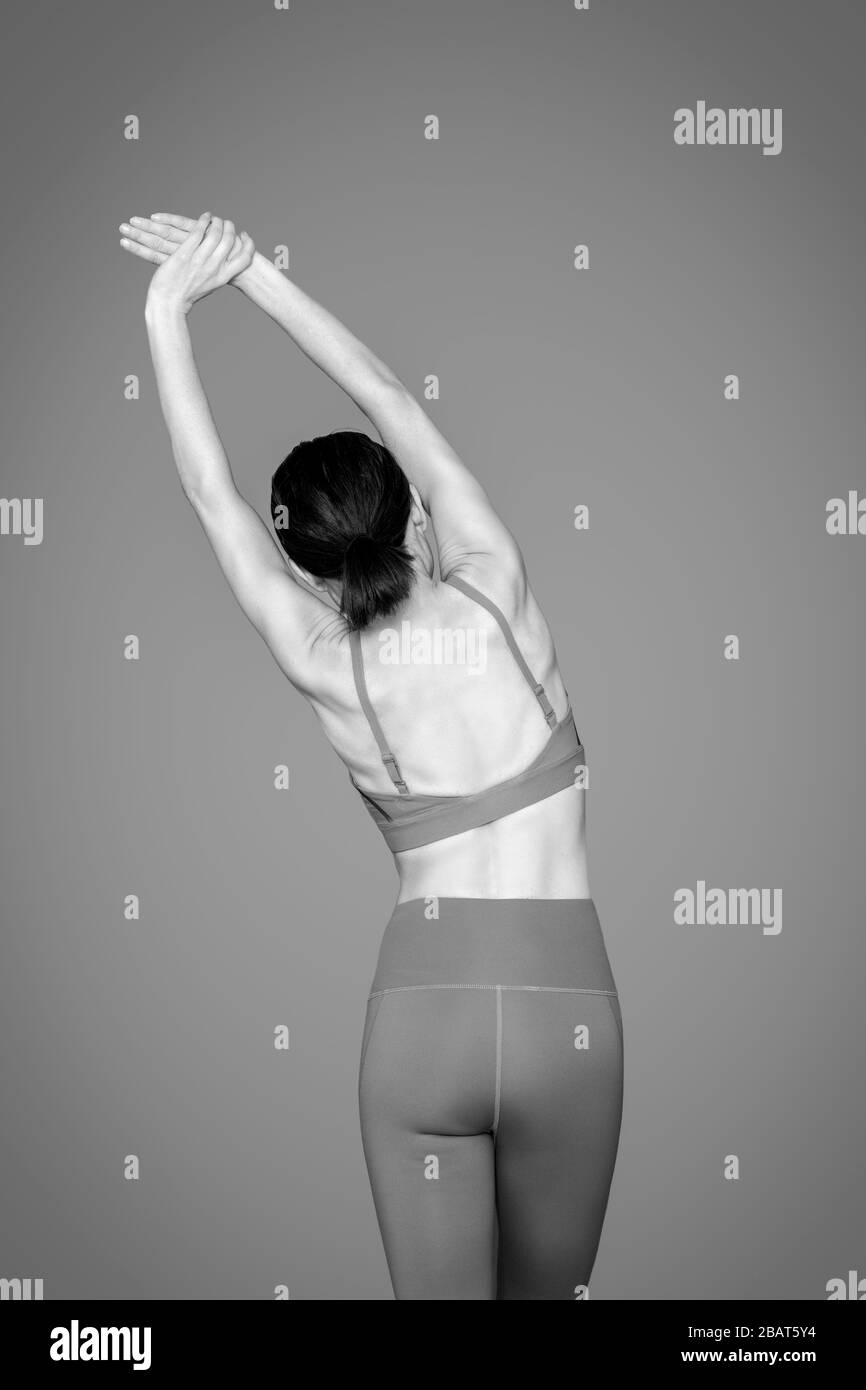 Rückansicht einer sportlichen Frau mit Dehnung, Aufwärmübungen, schwarz-weiß. Stockfoto