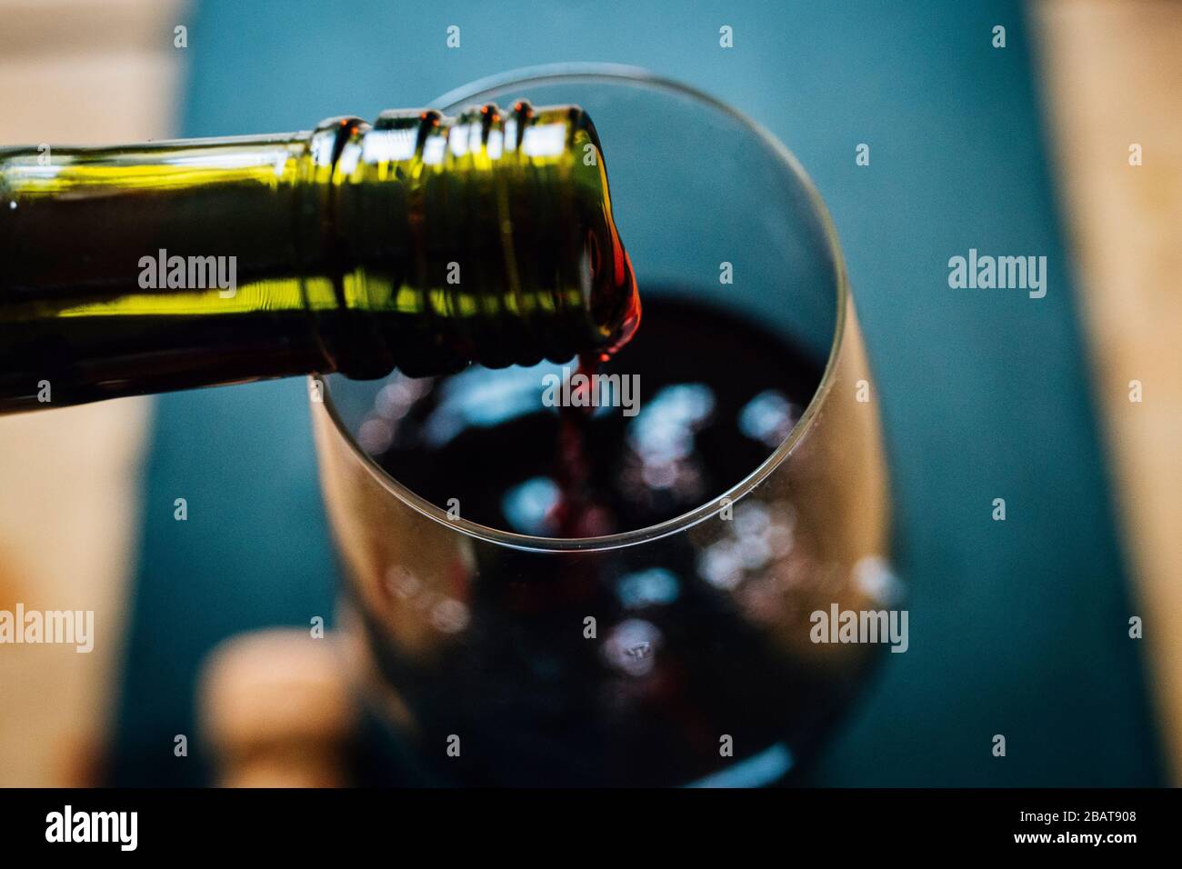 Nahaufnahme von Rotwein, der aus einer Flasche in ein Weinglas gegossen wird. Ansicht von oben. Verschwommener Hintergrund, geringe Schärfentiefe Stockfoto