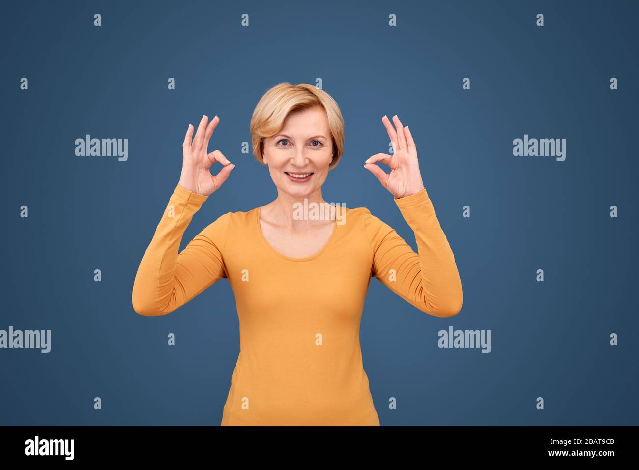 Freistil. Reife Frau stehend isoliert auf blau zeigt zen Geste glücklich Stockfoto