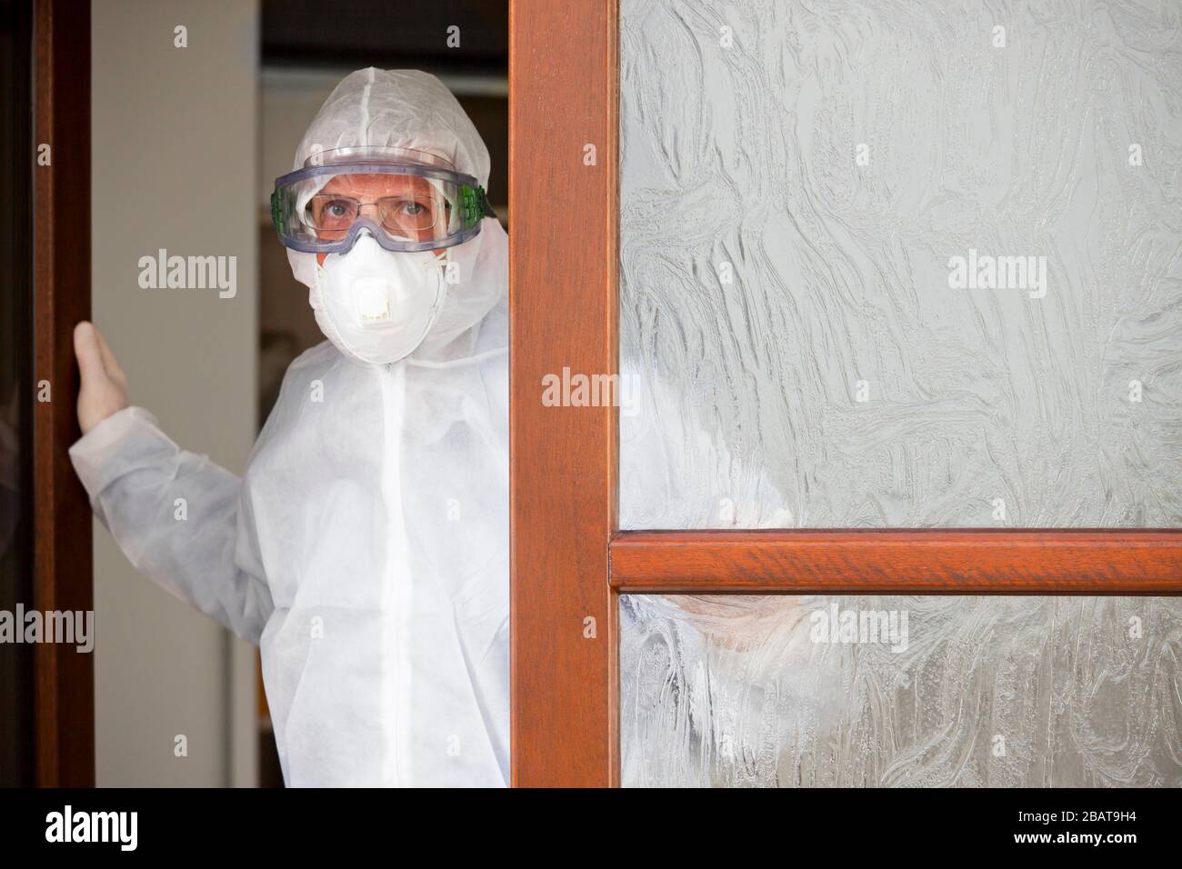 Der Arzt mit Schutzkleidung und Operationsmaske verlässt ein Krankenhaus mit Coronavirus-Patienten Stockfoto