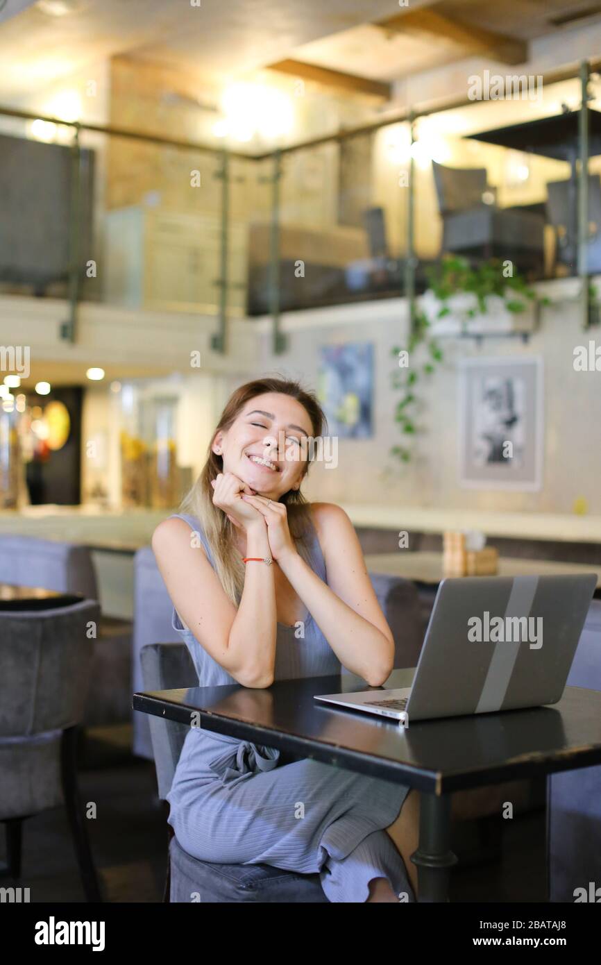 Junges Mädchen, das im Café sitzt und mit einem Laptop im Internet surft. Stockfoto