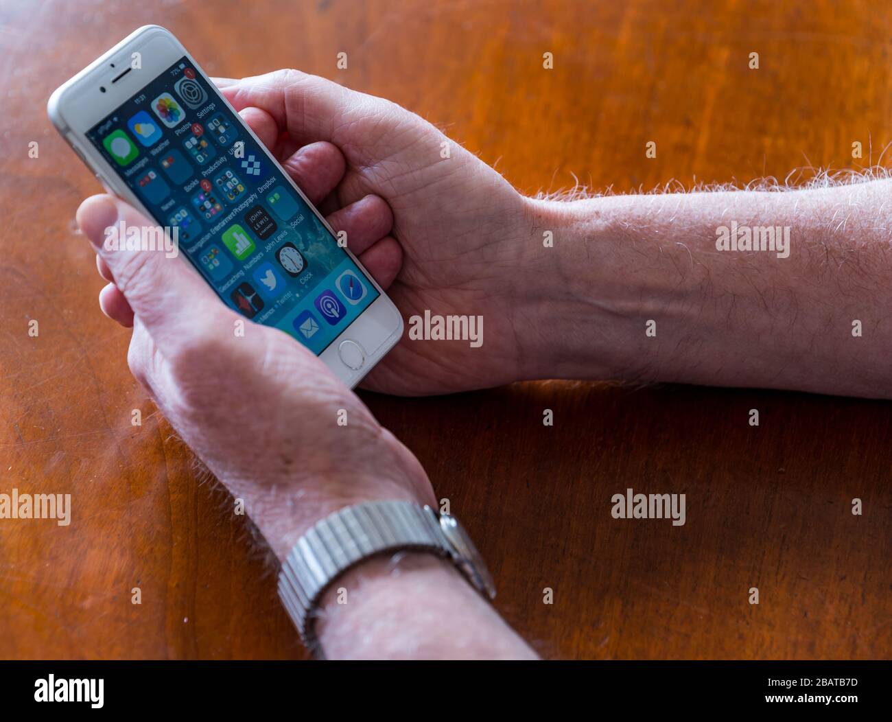 Senior man hält Mobiltelefon mit Apps auf dem Hauptbildschirm, Großbritannien Stockfoto