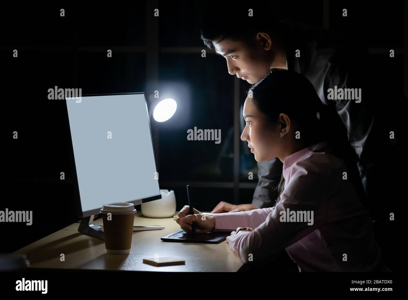 Junge Erwachsene asiatische Unternehmer diskutieren mit Kollegen über die Arbeit spät in der Nacht in ihrem Büro mit Computer. Mit so hart arbeiten und arbeiten l Stockfoto