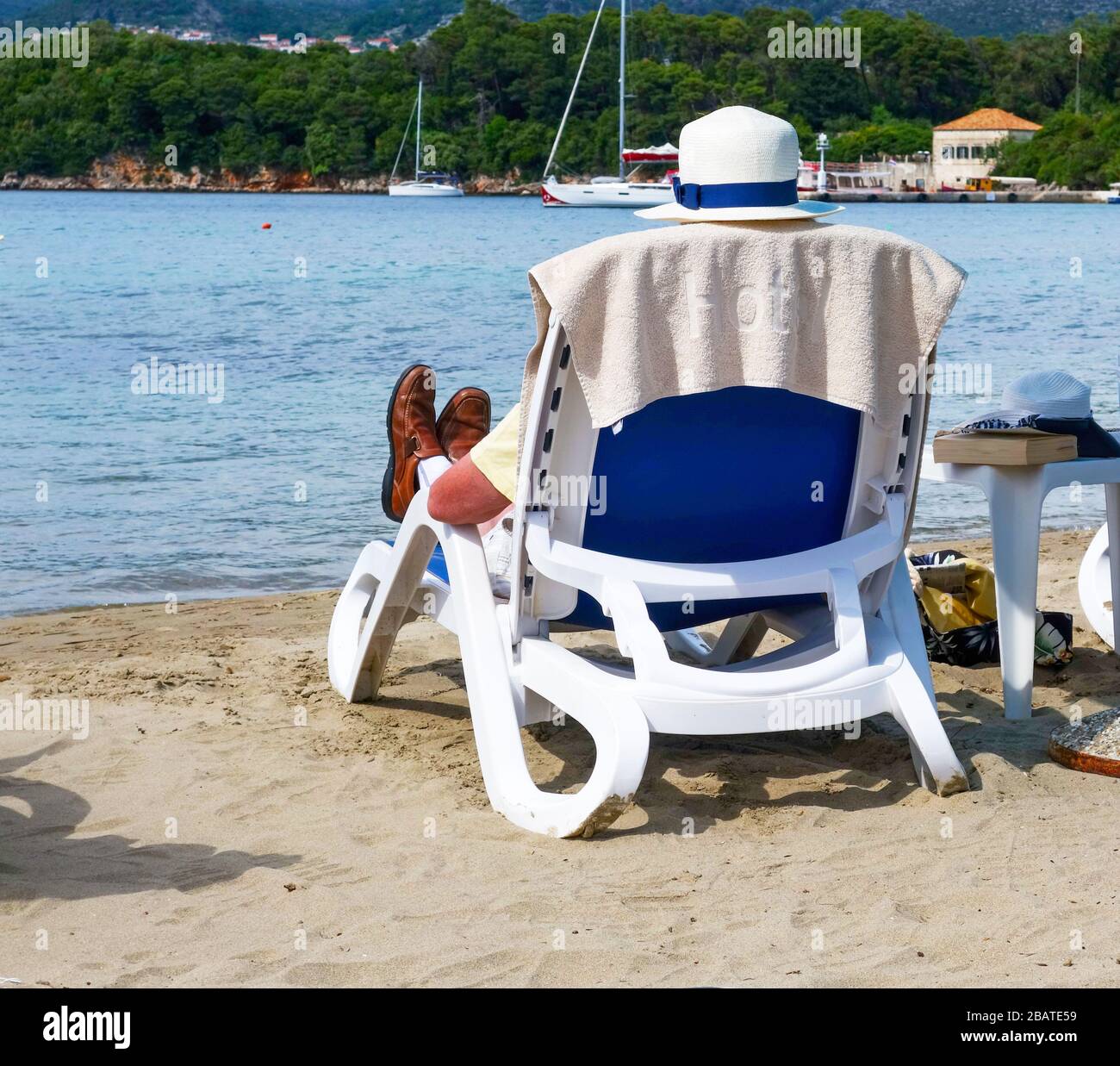 Ein Mann, der sich auf einer Sonnenliege am Strand im TUI Sensimar Kalamota Island Resort Hotel, Koločep, Elaphiti Islands, Kroatien, Europa, entspannen kann Stockfoto