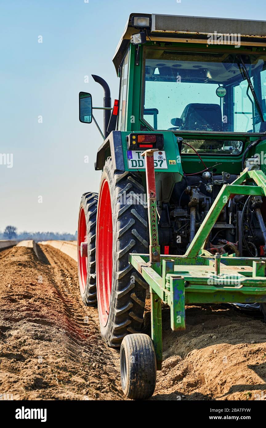 Brandenburg, Deutschland - 28. März 2020: Sie blicken an einem Traktor vorbei auf ein Spargelfeld in Deutschland. Der Schwerpunkt liegt auf dem Reifen des Traktors, dem Horizont Stockfoto