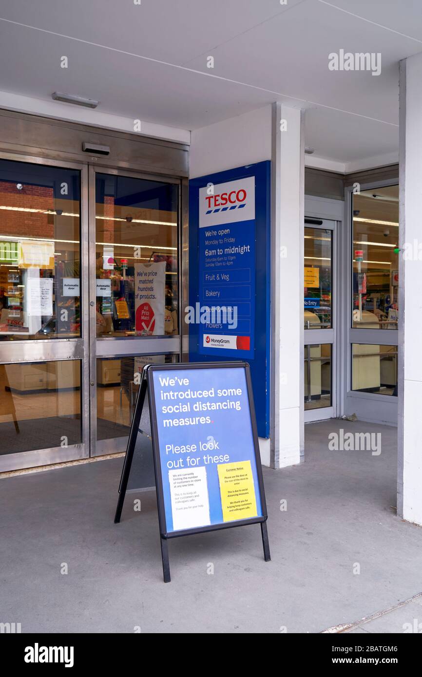 Soziale Distanzierungsmaßnahmen Informationsschild vor dem Eingang zu einem Tesco Supermarkt während der Covid-19 Coronavirus Notfall Stockfoto