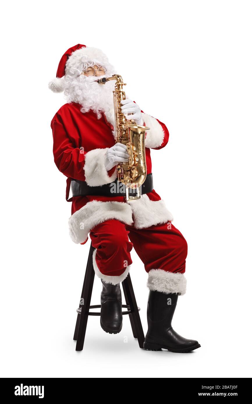 Weihnachtsmann sitzt auf einem Stuhl und spielt ein Saxofon isoliert auf weißem Hintergrund Stockfoto